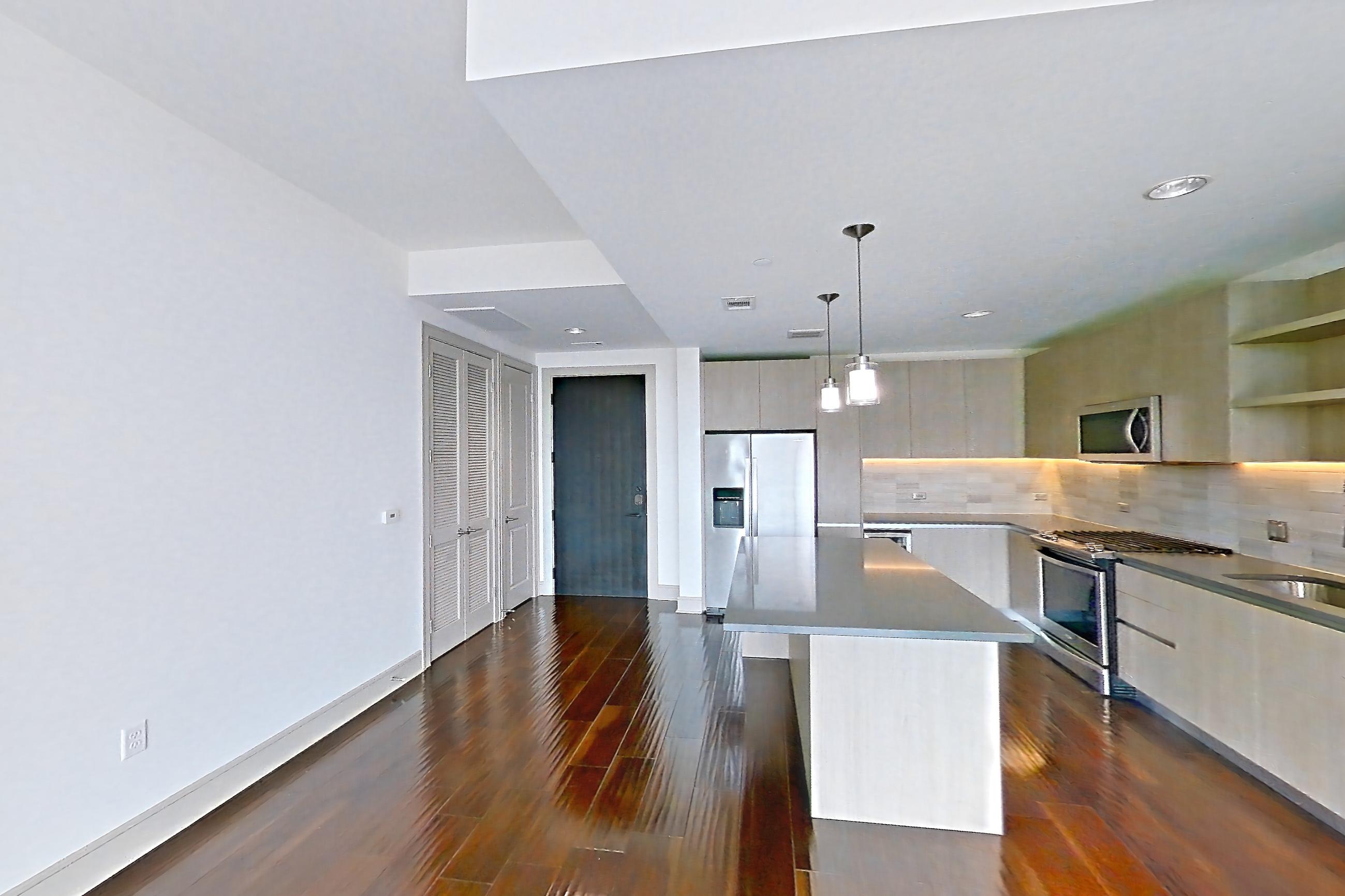 Living room with dark wood-finish flooring, dishwasher, gas range, oven/range, refrigerator, stainless steel appliances, and water & ice dispenser, Apartment 1307 at Cortland Museum District