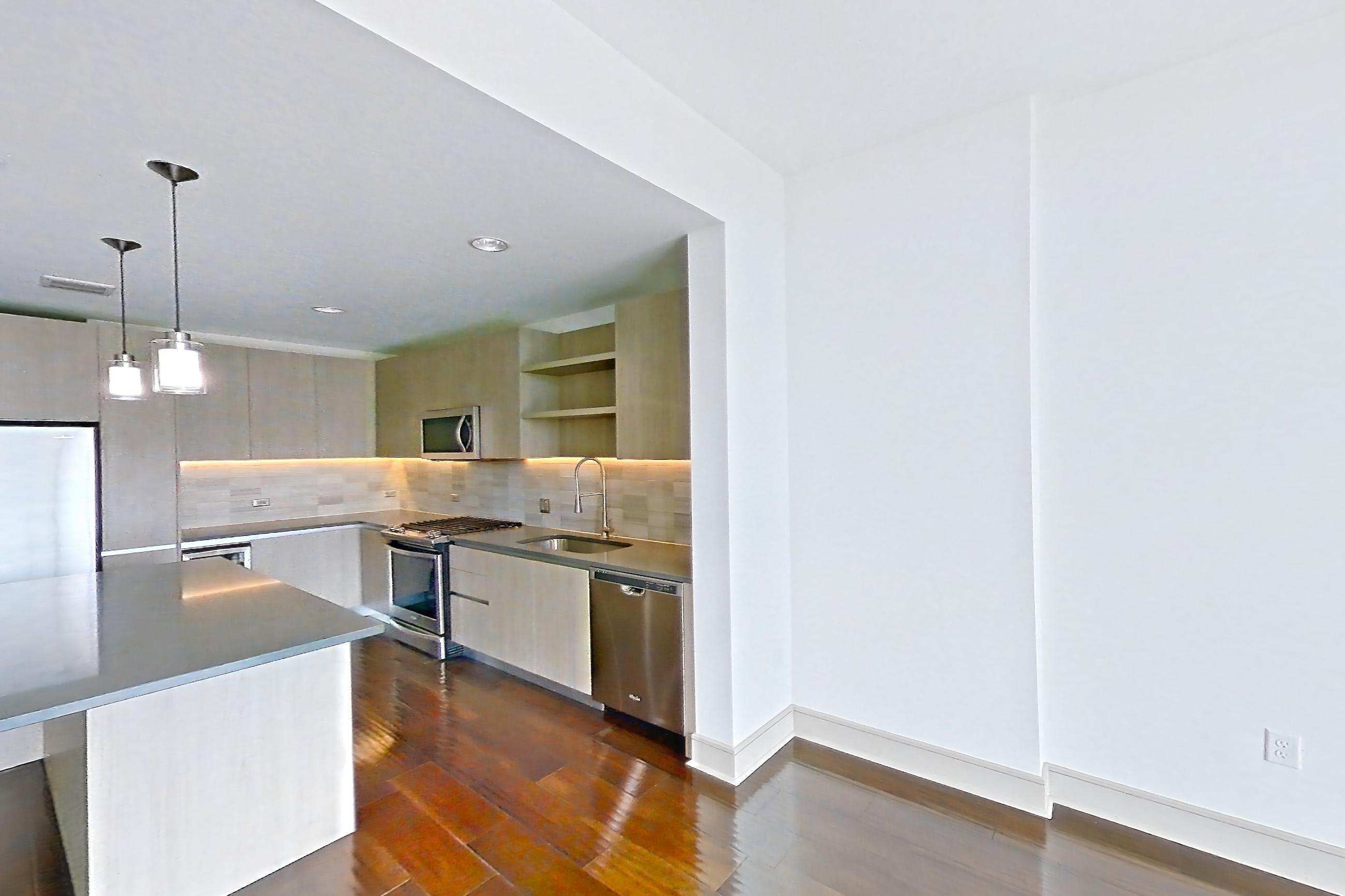 Living room with dark wood-finish flooring, dishwasher, gas range, oven/range, refrigerator, stainless steel appliances, and water & ice dispenser, Apartment 1307 at Cortland Museum District