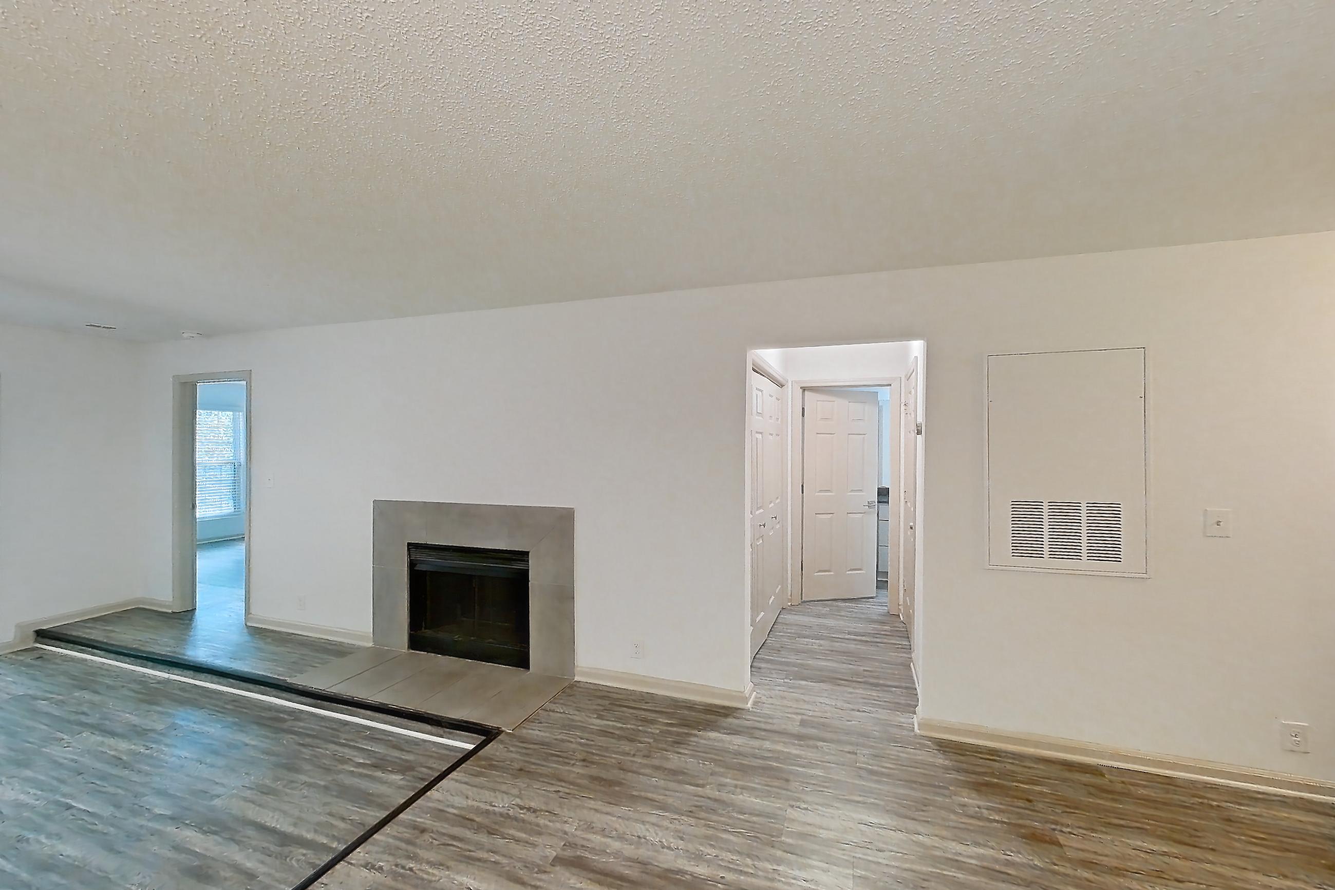 Dining room with dark stone countertops, dark wood-finish flooring, dishwasher, electric range, fireplace, light countertops, light wood-finish flooring, microwave, oven/range, refrigerator, stainless steel appliances, tile fireplace, and white appliances, Apartment 3 at Cortland Cotswold