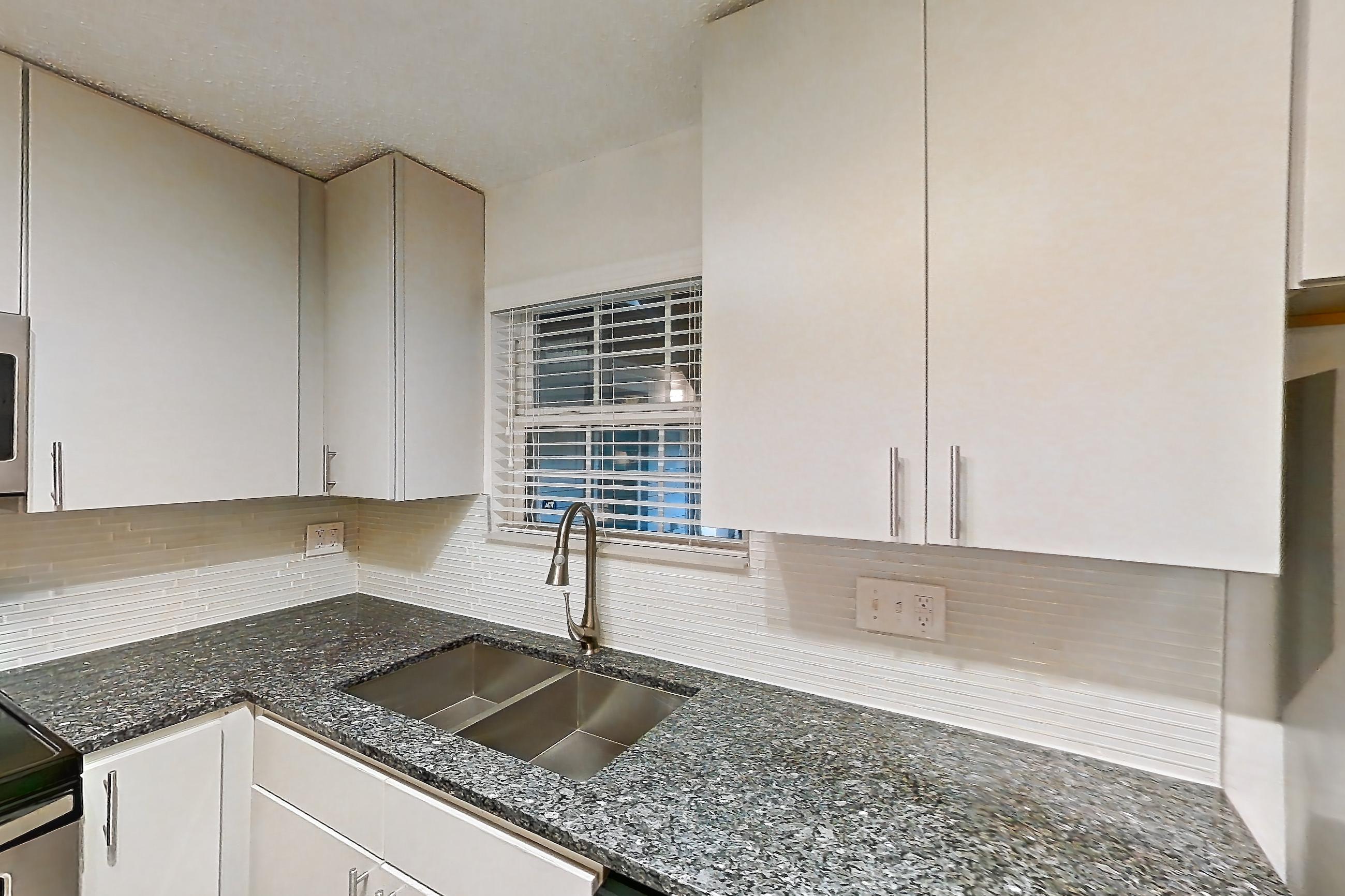 Kitchen with dark stone countertops, dishwasher, electric range, fireplace, light countertops, light wood-finish flooring, microwave, oven/range, refrigerator, and stainless steel appliances, Apartment 3 at Cortland Cotswold