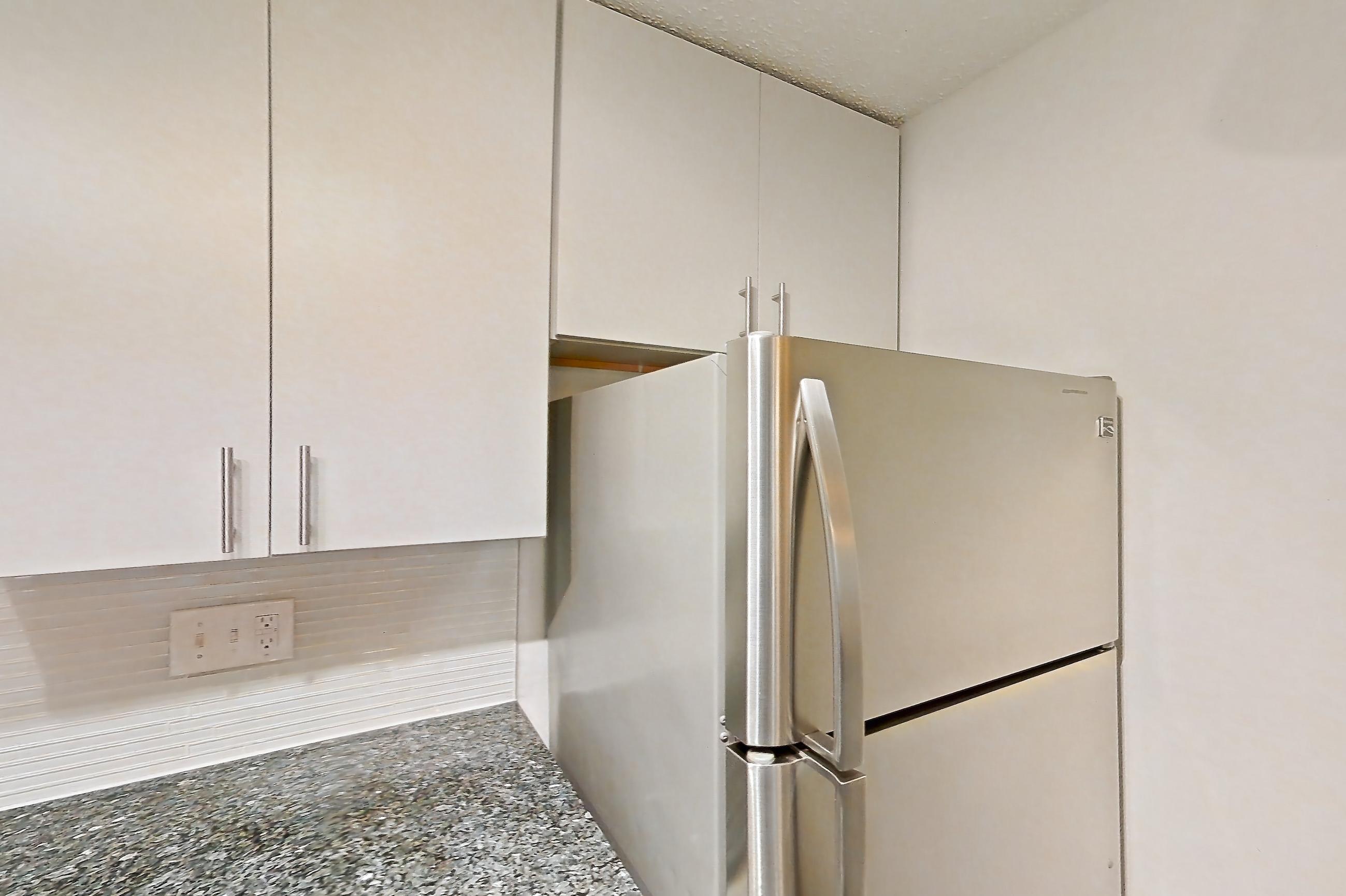 Kitchen with dark stone countertops, dishwasher, electric range, fireplace, light countertops, light wood-finish flooring, microwave, oven/range, refrigerator, and stainless steel appliances, Apartment 3 at Cortland Cotswold