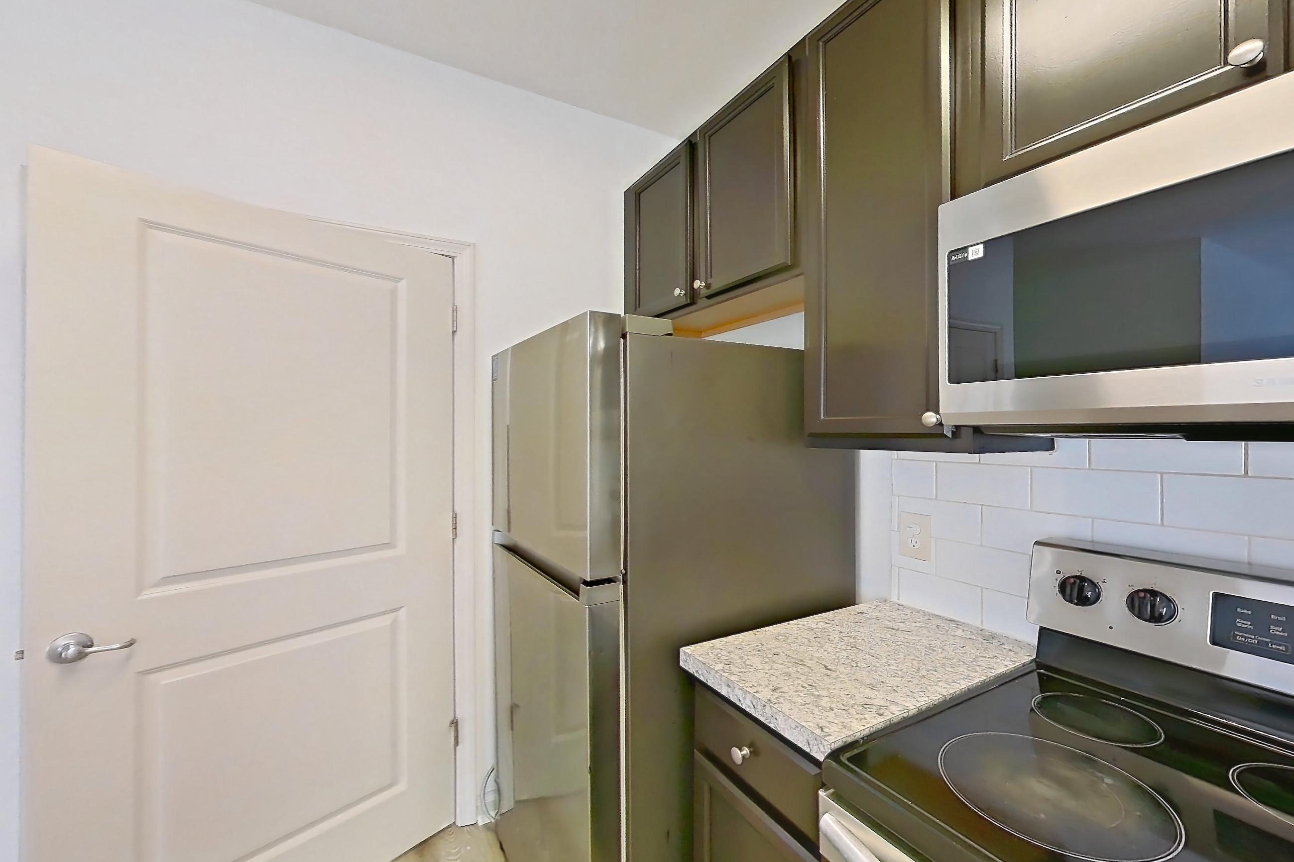 Kitchen with dishwasher, electric range, light countertops, light wood-finish flooring, microwave, oven/range, refrigerator, and stainless steel appliances, Apartment 105-4808 at Cortland Hilliard