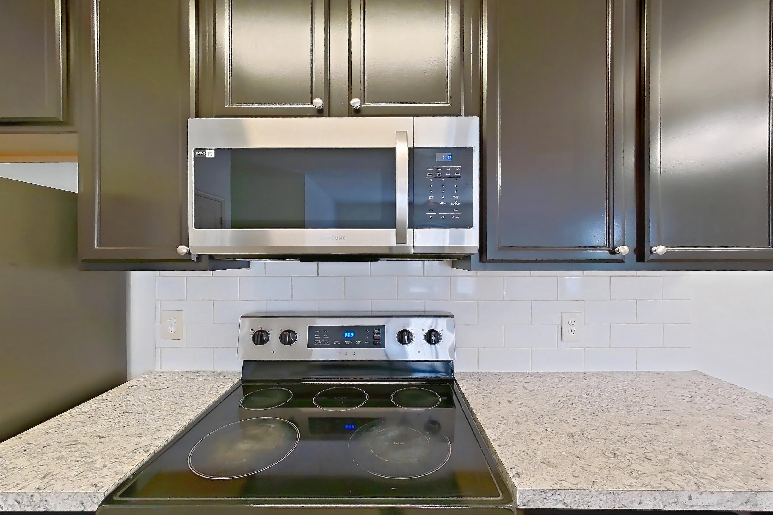 Kitchen with dishwasher, electric range, light countertops, light wood-finish flooring, microwave, oven/range, refrigerator, and stainless steel appliances, Apartment 105-4808 at Cortland Hilliard