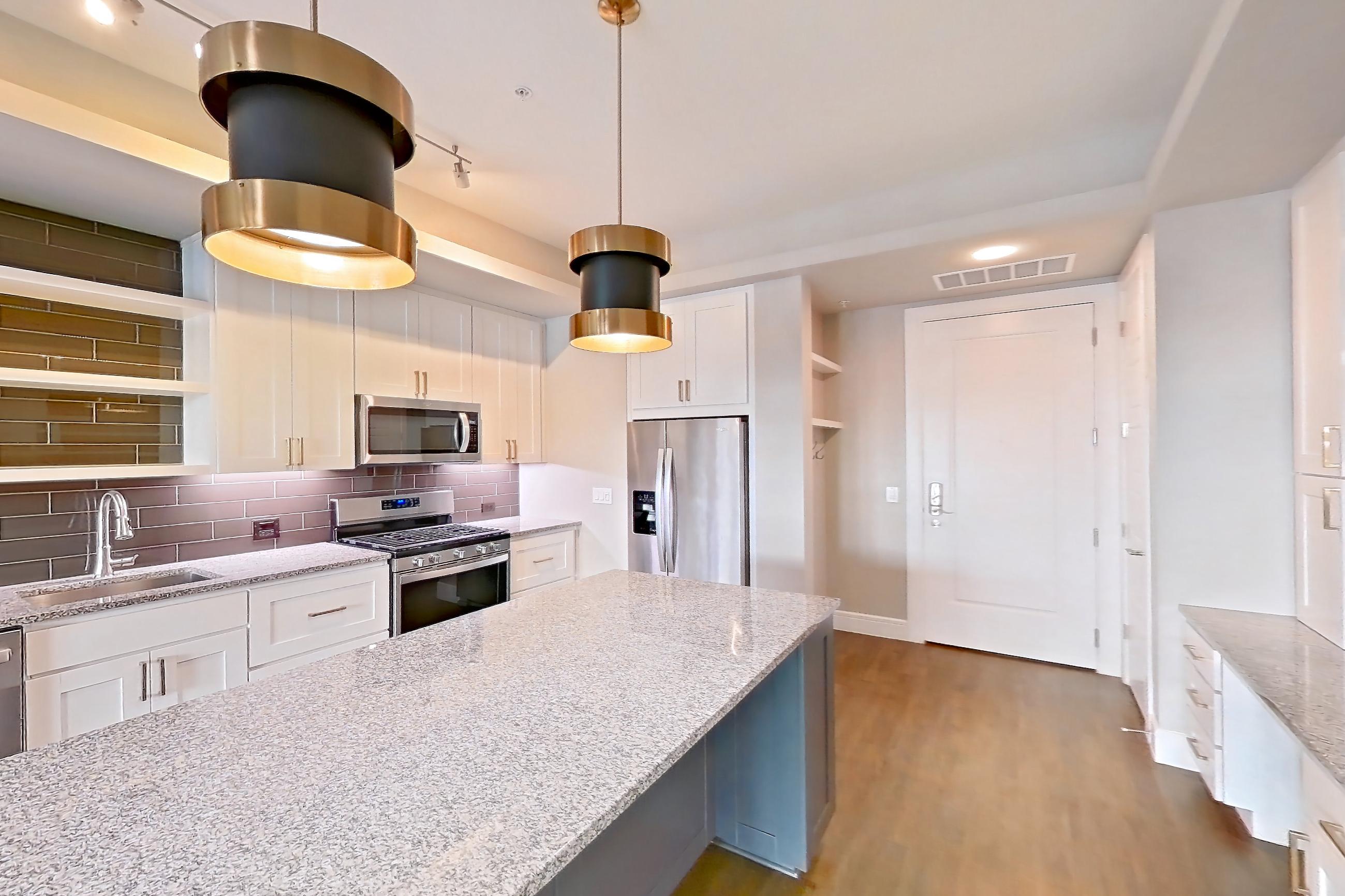 Dining room with dark wood-finish flooring, dishwasher, gas range, light countertops, light stone countertops, oven/range, and stainless steel appliances, Apartment 105 at Cortland Biltmore
