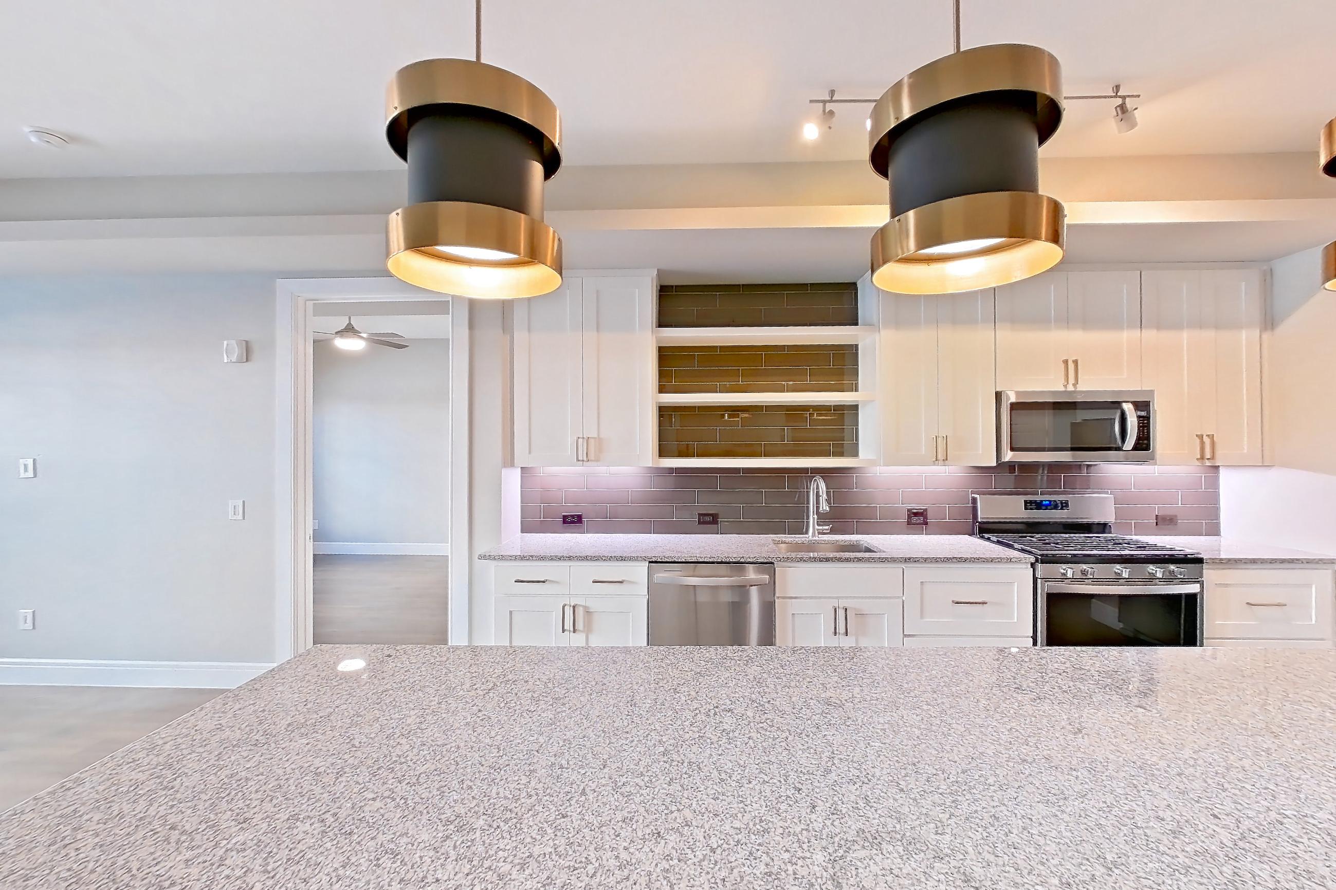 Dining room with dark wood-finish flooring, dishwasher, gas range, light countertops, light stone countertops, oven/range, and stainless steel appliances, Apartment 105 at Cortland Biltmore