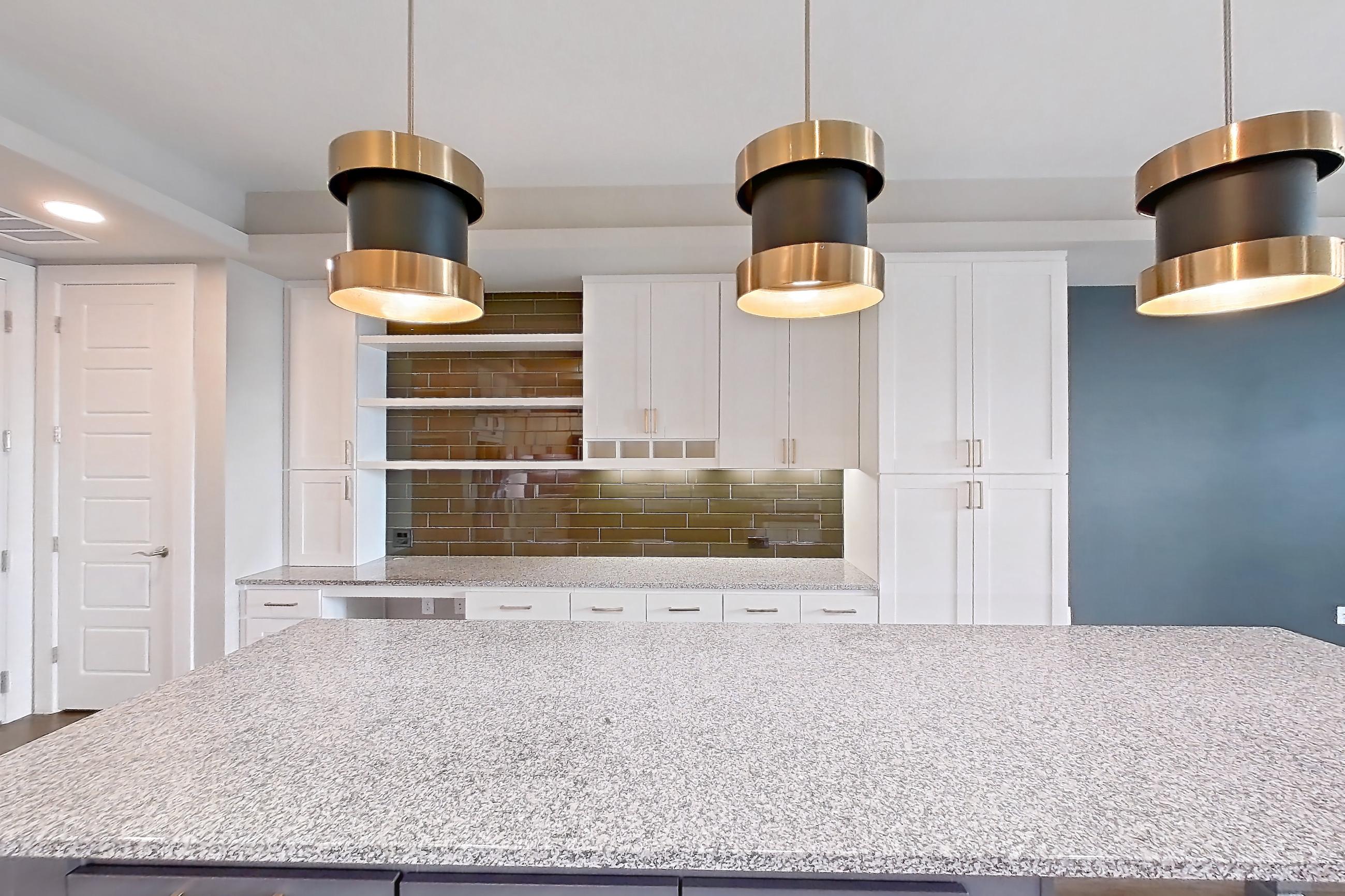 Kitchen with dark wood-finish flooring, dishwasher, gas range, light countertops, light stone countertops, oven/range, refrigerator, stainless steel appliances, and water & ice dispenser, Apartment 105 at Cortland Biltmore