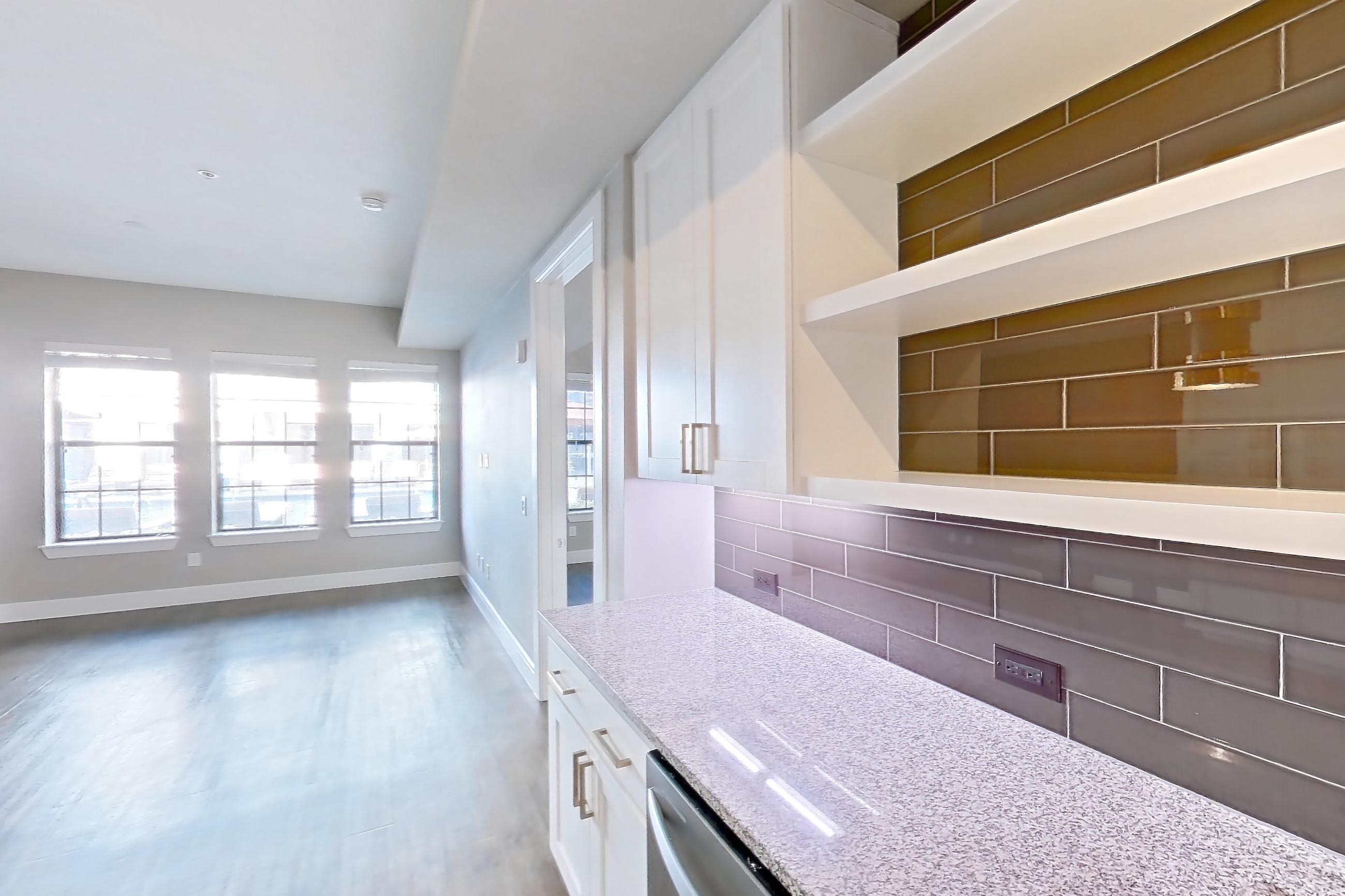 Kitchen with dark wood-finish flooring, dishwasher, gas range, light countertops, light stone countertops, oven/range, refrigerator, stainless steel appliances, and water & ice dispenser, Apartment 105 at Cortland Biltmore