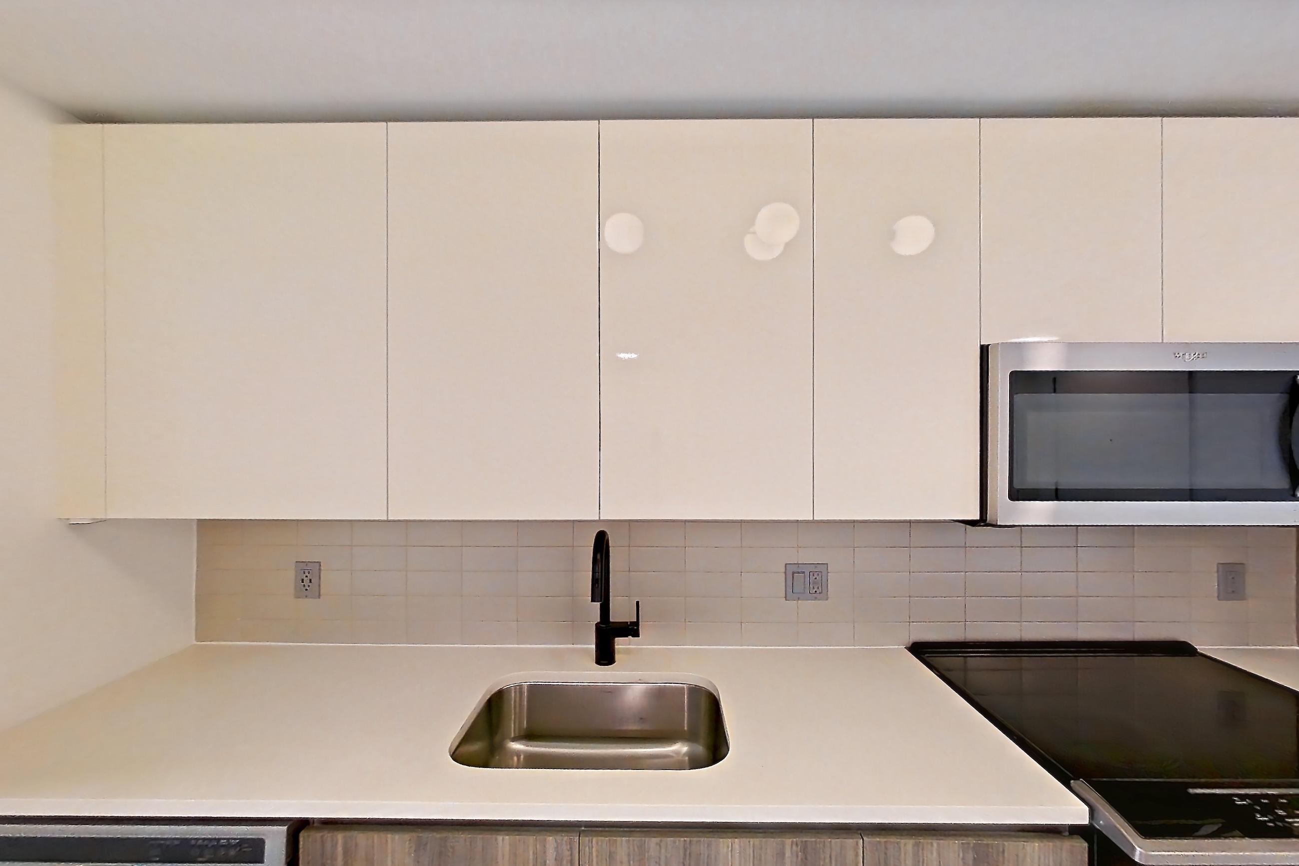 Kitchen with dishwasher, electric range, light countertops, light tile flooring, light wood-finish flooring, microwave, oven/range, refrigerator, stainless steel appliances, water & ice dispenser, and wood-look tile flooring, Apartment 1016 at Cortland Midtown Miami