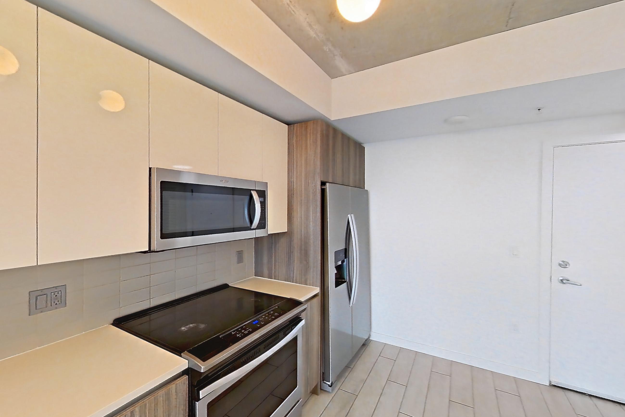 Kitchen with dishwasher, electric range, light countertops, light tile flooring, light wood-finish flooring, microwave, oven/range, refrigerator, stainless steel appliances, water & ice dispenser, and wood-look tile flooring, Apartment 2416 at Cortland Midtown Miami
