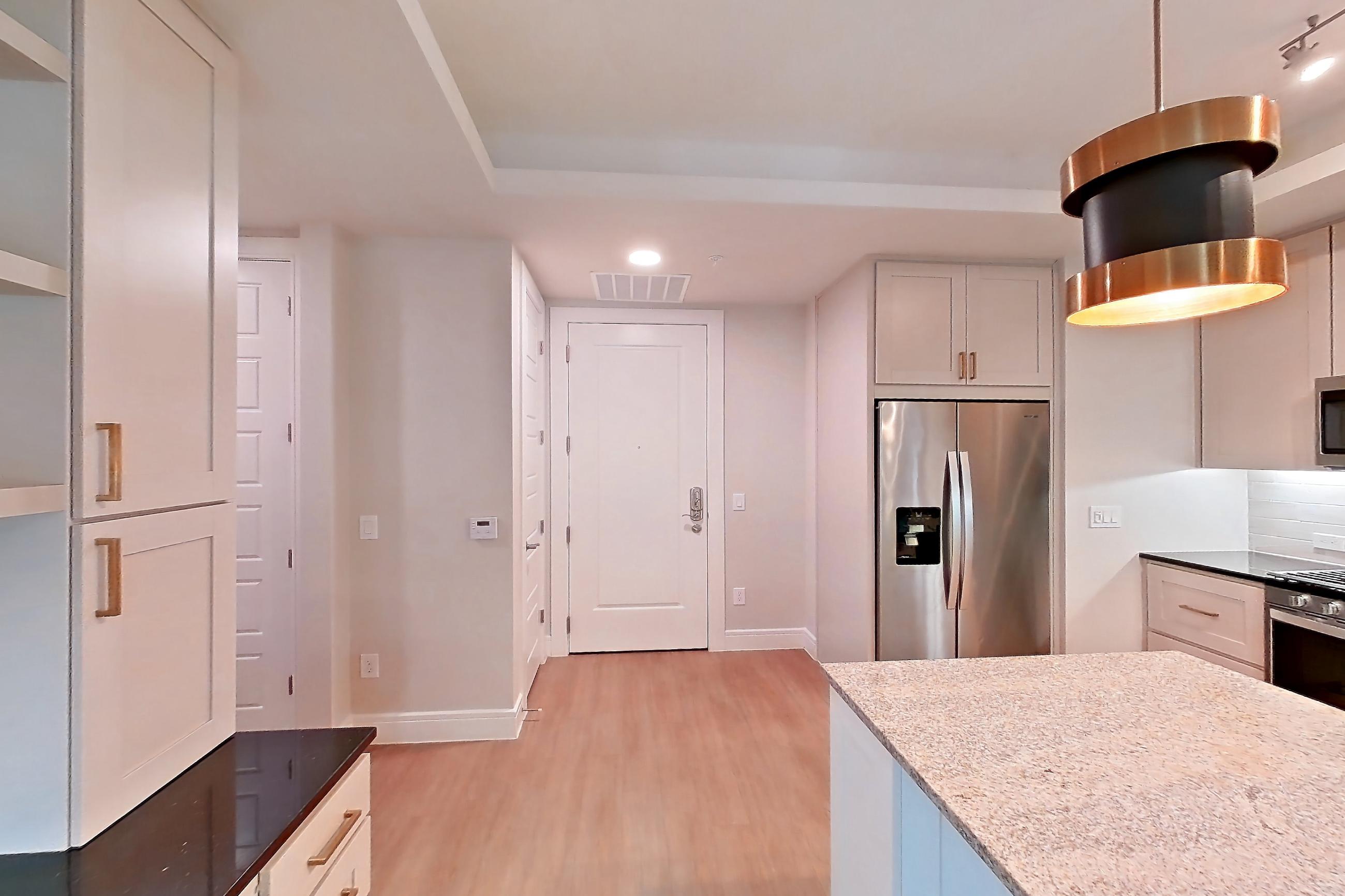 Dining room with dark stone countertops, dishwasher, gas range, light countertops, light stone countertops, light wood-finish flooring, oven/range, refrigerator, stainless steel appliances, and water & ice dispenser, Apartment 234 at Cortland Biltmore