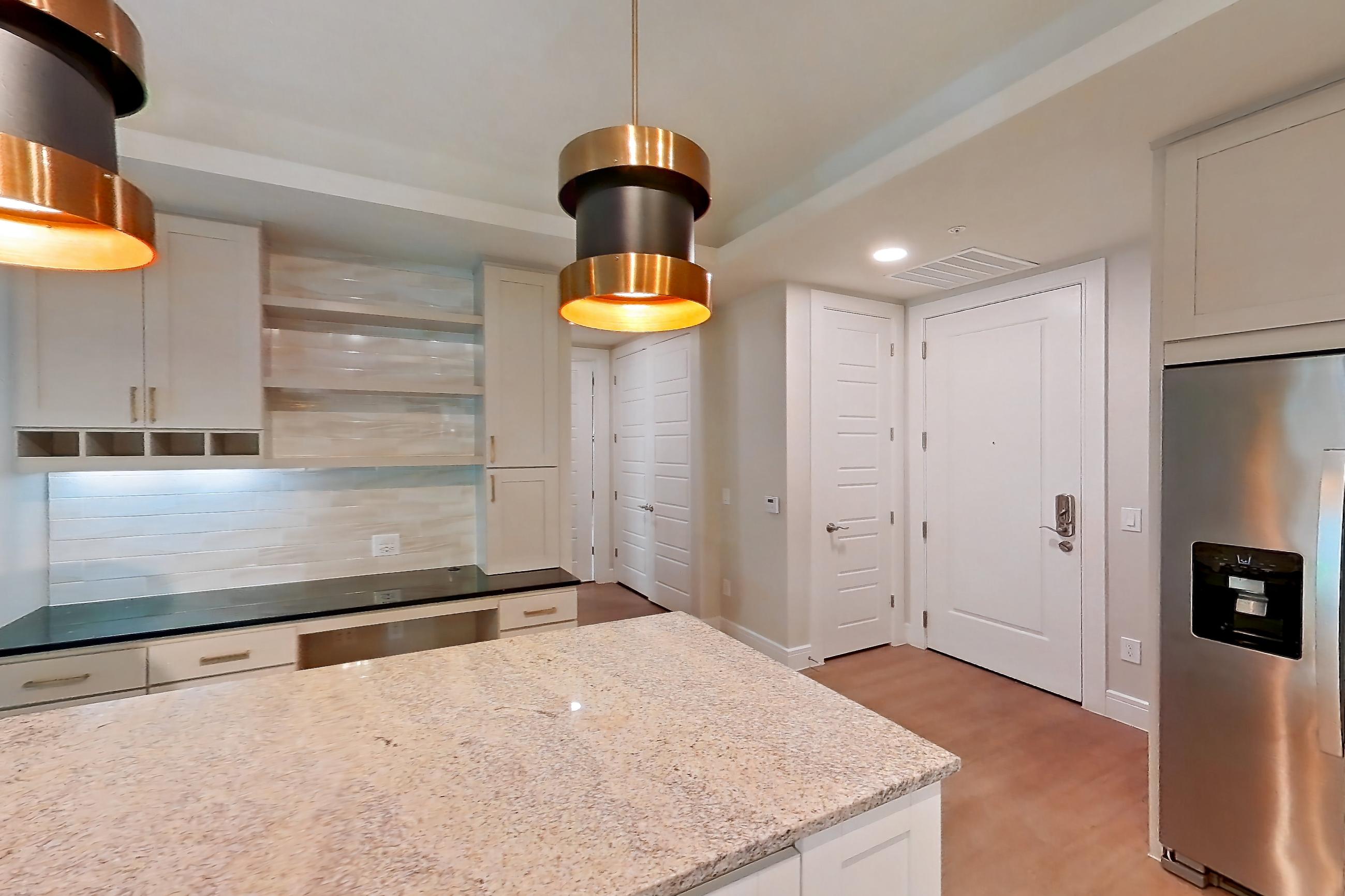 Kitchen with dark stone countertops, dishwasher, gas range, light countertops, light stone countertops, light wood-finish flooring, oven/range, and stainless steel appliances, Apartment 234 at Cortland Biltmore