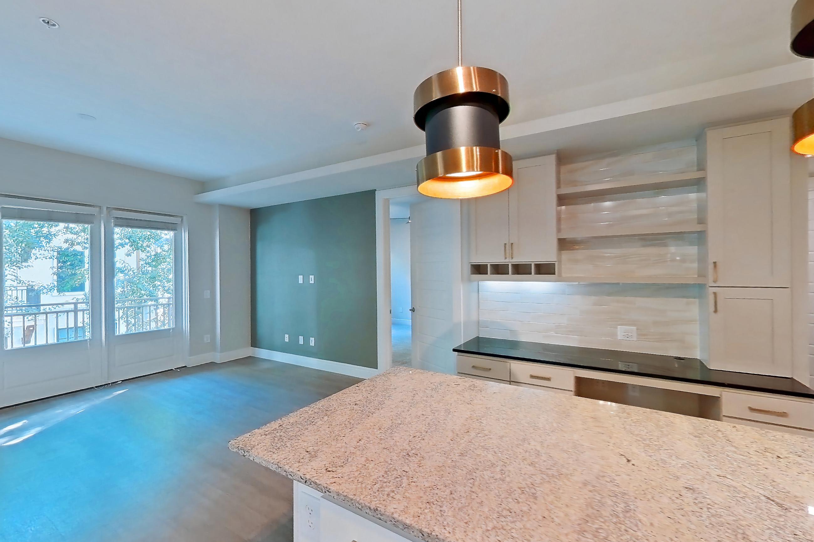 Kitchen with dark stone countertops, dishwasher, gas range, light countertops, light stone countertops, light wood-finish flooring, oven/range, and stainless steel appliances, Apartment 234 at Cortland Biltmore