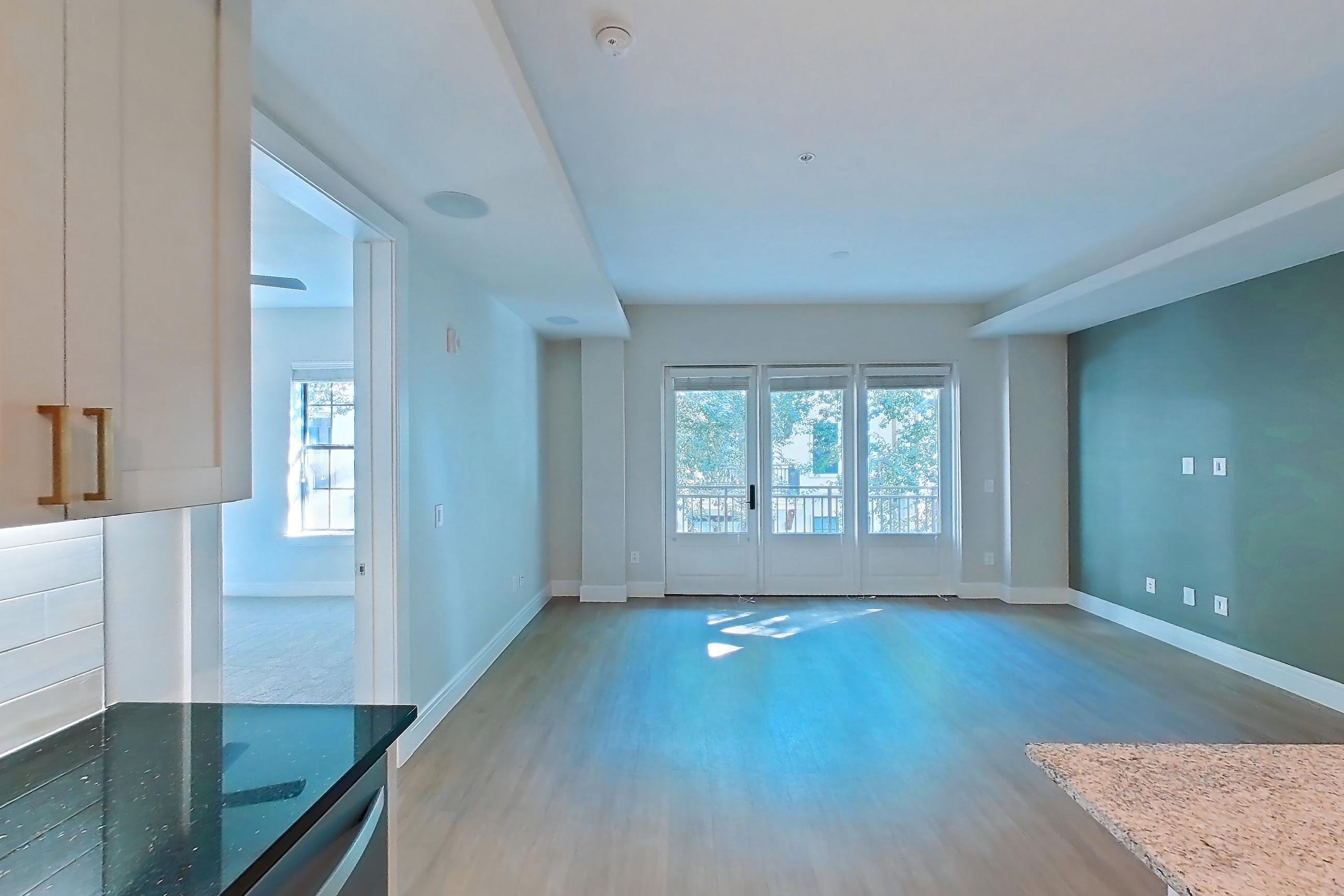 Kitchen with dark stone countertops, dishwasher, gas range, light countertops, light stone countertops, light wood-finish flooring, oven/range, and stainless steel appliances, Apartment 234 at Cortland Biltmore