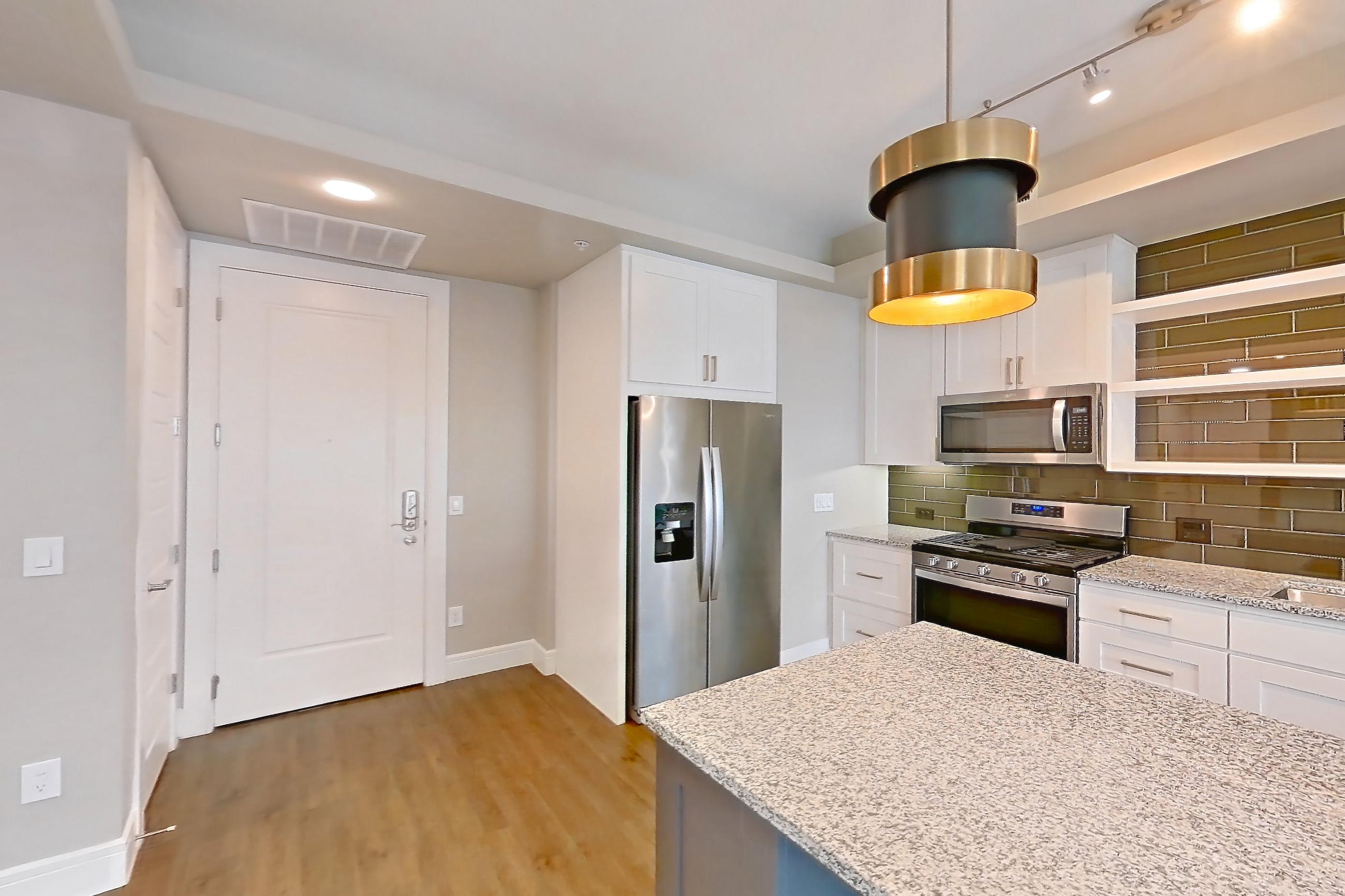 Dining room with dark wood-finish flooring, dishwasher, gas range, light countertops, light stone countertops, oven/range, refrigerator, stainless steel appliances, and water & ice dispenser, Apartment 317 at Cortland Biltmore