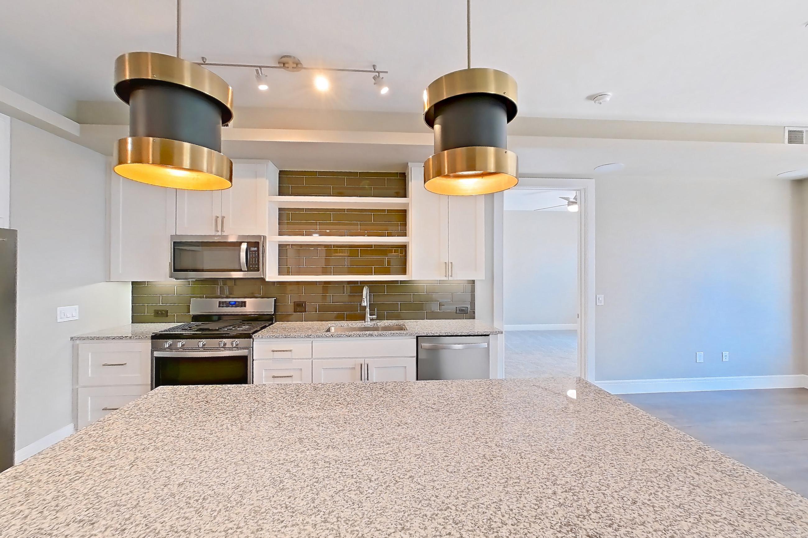 Dining room with dark wood-finish flooring, dishwasher, gas range, light countertops, light stone countertops, oven/range, refrigerator, stainless steel appliances, and water & ice dispenser, Apartment 317 at Cortland Biltmore