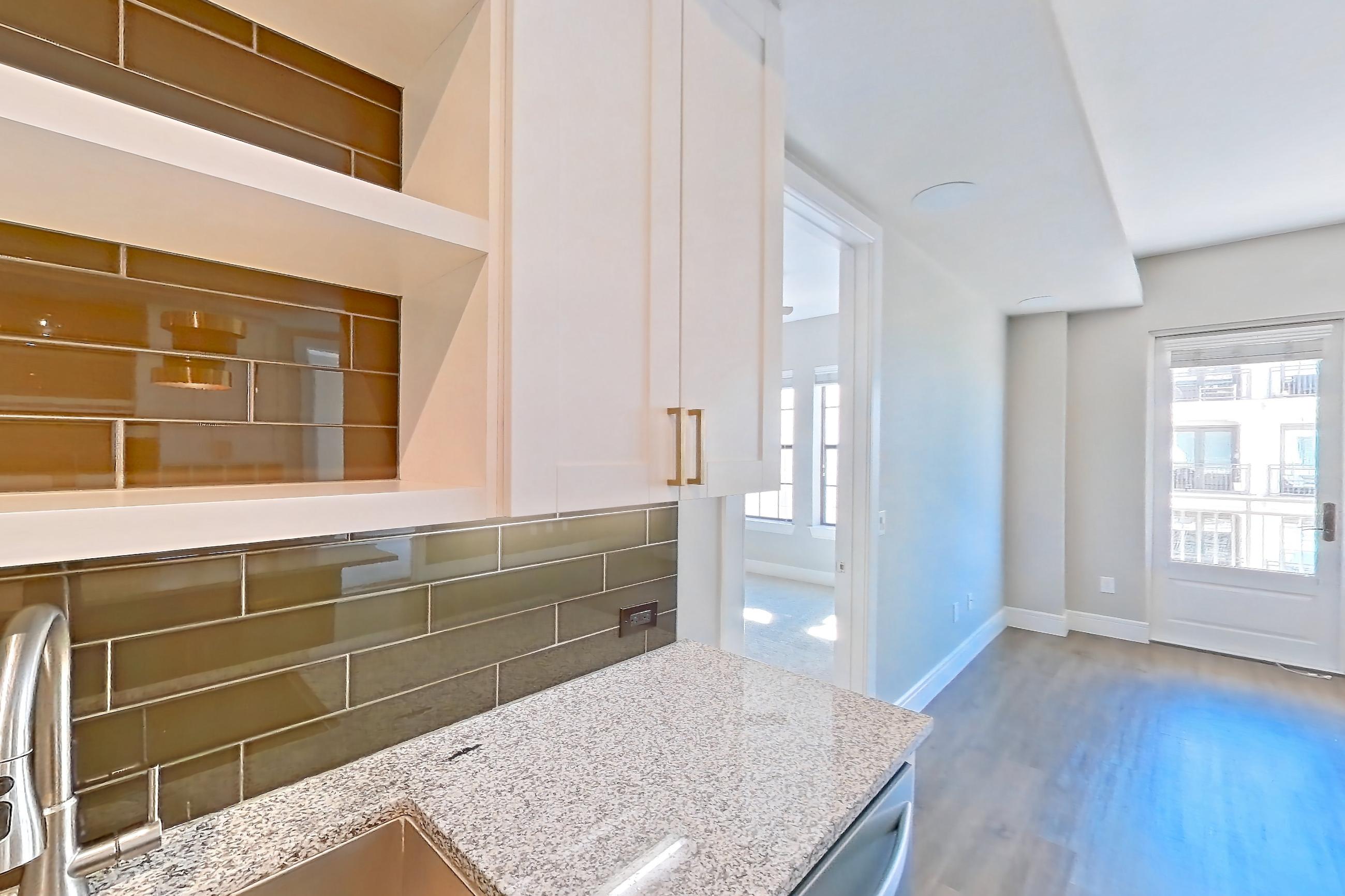 Kitchen with dark wood-finish flooring, dishwasher, gas range, light countertops, light stone countertops, light wood-finish flooring, oven/range, refrigerator, stainless steel appliances, and water & ice dispenser, Apartment 317 at Cortland Biltmore