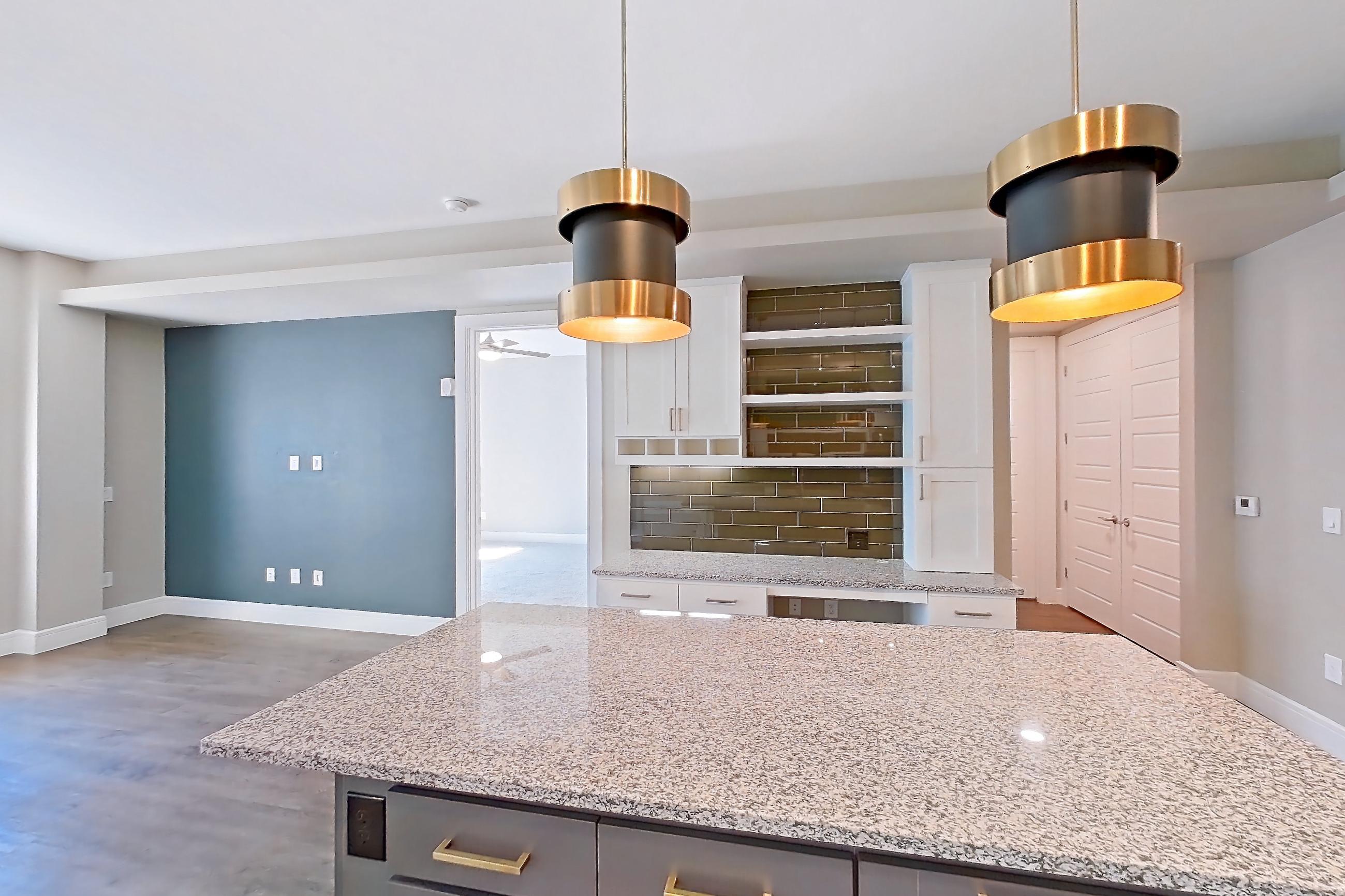 Kitchen with dark wood-finish flooring, dishwasher, gas range, light countertops, light stone countertops, light wood-finish flooring, oven/range, refrigerator, stainless steel appliances, and water & ice dispenser, Apartment 317 at Cortland Biltmore
