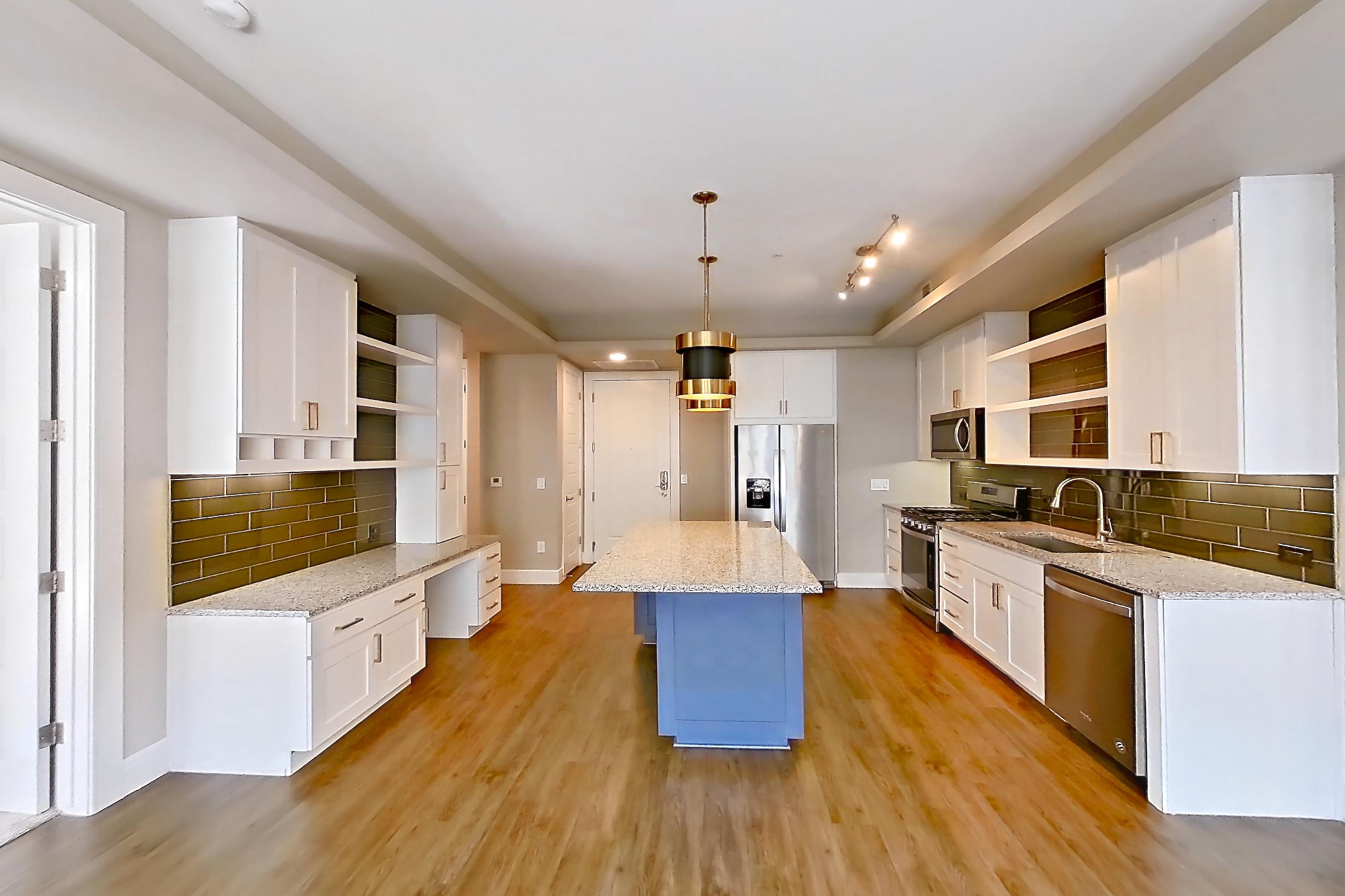 Living room with dark wood-finish flooring, dishwasher, gas range, light countertops, light stone countertops, oven/range, refrigerator, stainless steel appliances, and water & ice dispenser, Apartment 317 at Cortland Biltmore