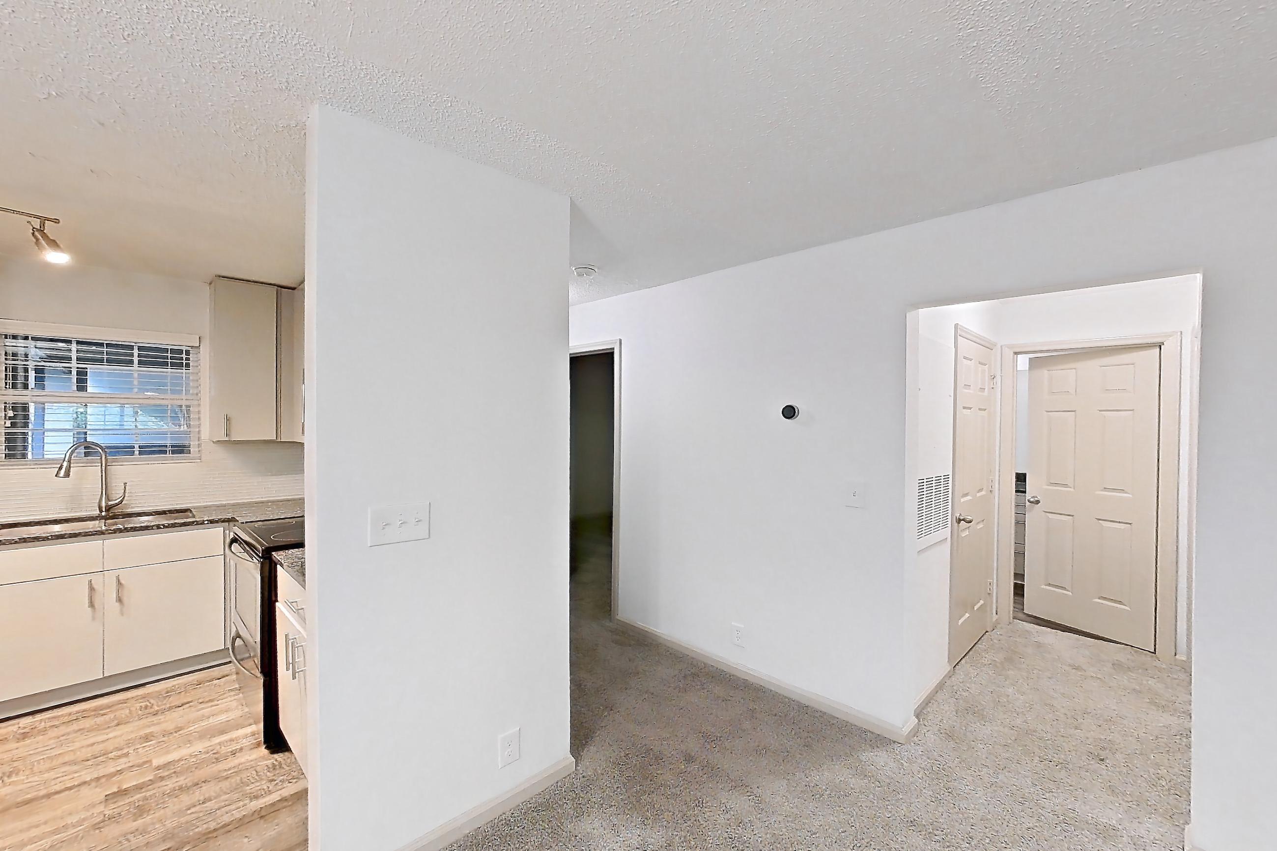 Dining room with dark stone countertops, dishwasher, fireplace, light carpet, refrigerator, stainless steel appliances, and tile fireplace, Apartment 12 at Cortland Cotswold