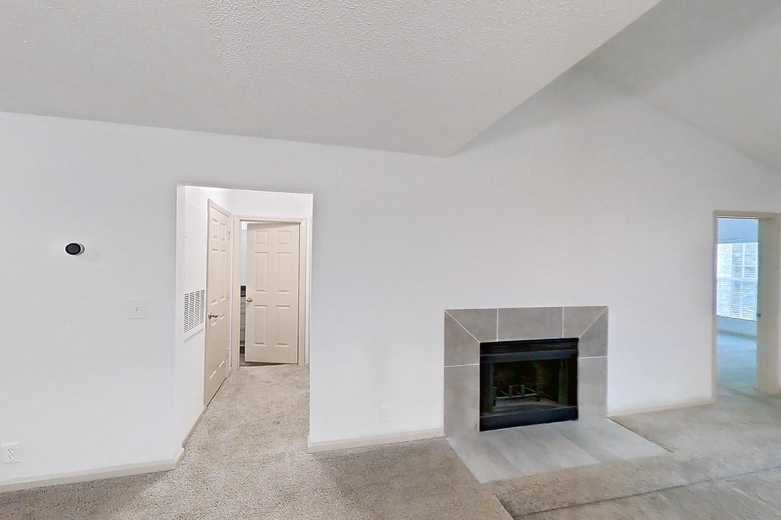 Dining room with dark stone countertops, dishwasher, fireplace, light carpet, refrigerator, stainless steel appliances, and tile fireplace, Apartment 12 at Cortland Cotswold