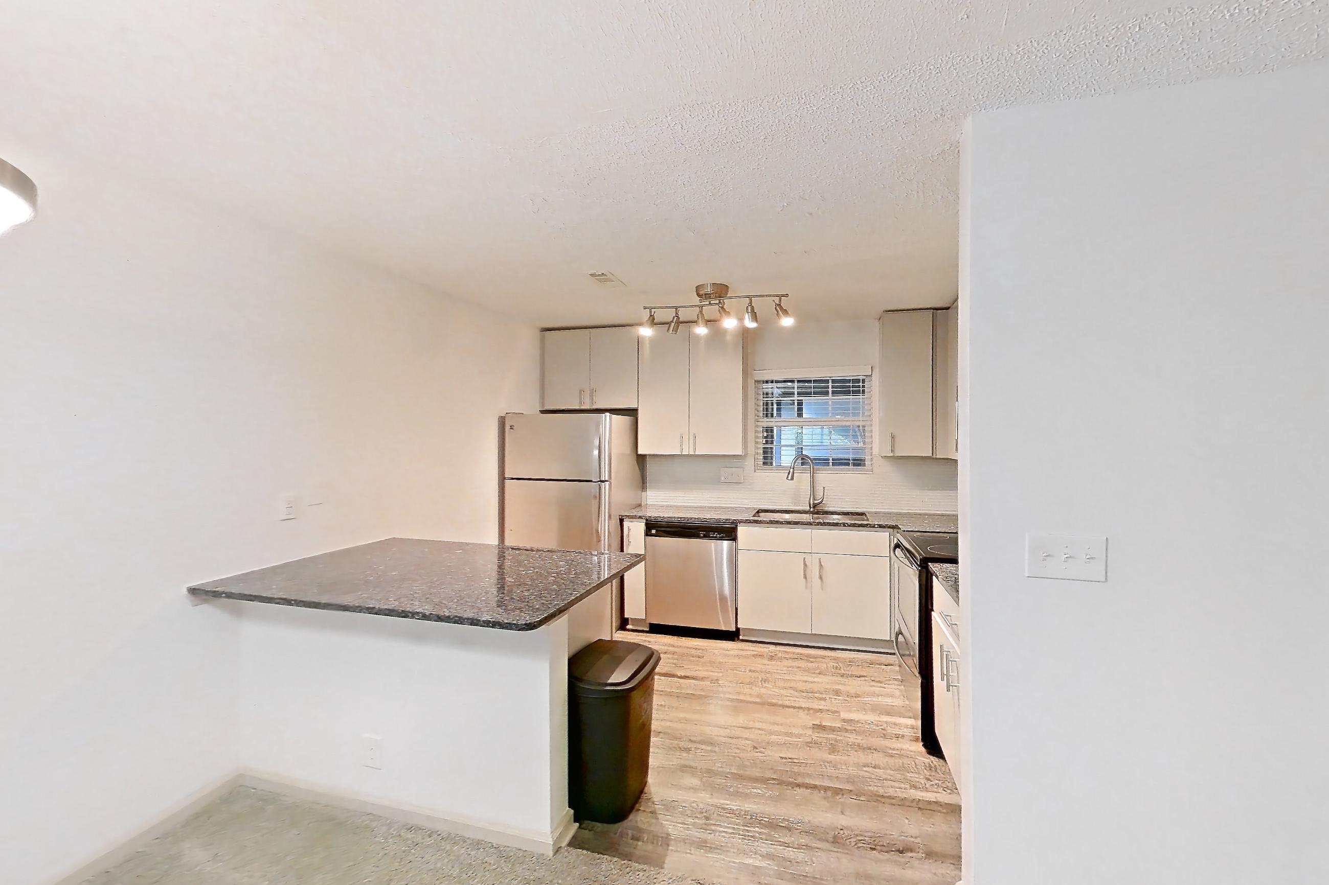 Dining room with dark stone countertops, dishwasher, fireplace, light carpet, refrigerator, stainless steel appliances, and tile fireplace, Apartment 12 at Cortland Cotswold