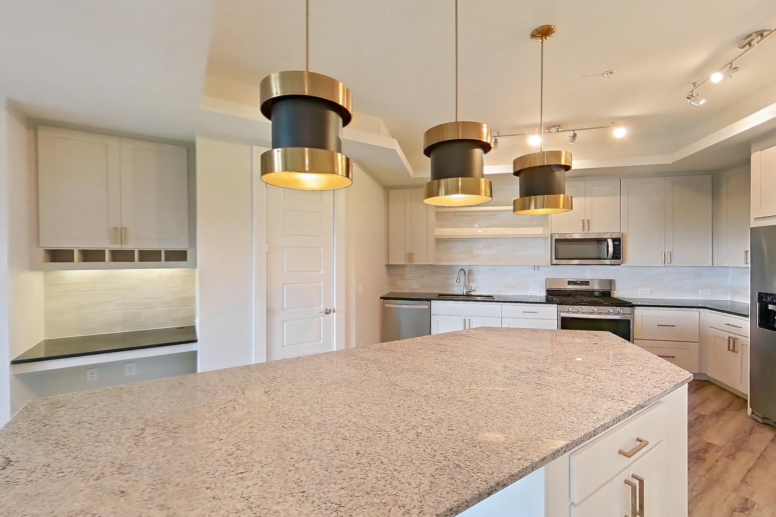 Dining room with dark stone countertops, dishwasher, light countertops, light stone countertops, light wood-finish flooring, and stainless steel appliances, Apartment 224 at Cortland Biltmore