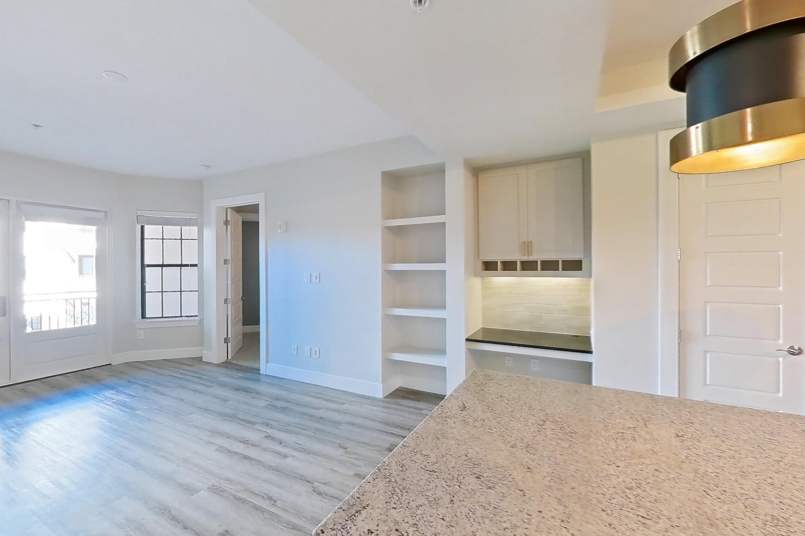 Dining room with dark stone countertops, dishwasher, light countertops, light stone countertops, light wood-finish flooring, and stainless steel appliances, Apartment 224 at Cortland Biltmore
