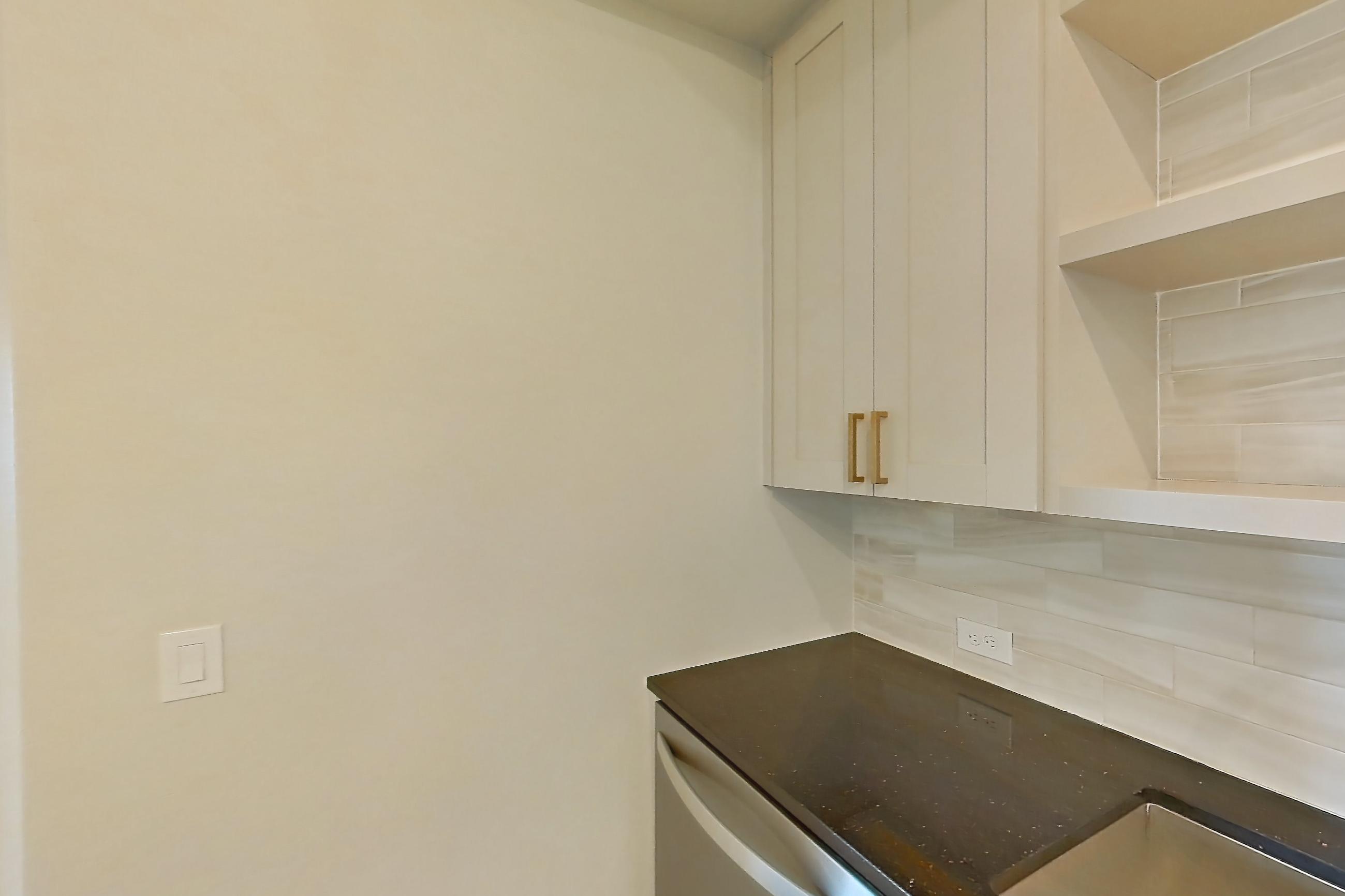 Kitchen with dark stone countertops, dishwasher, gas range, light countertops, light stone countertops, light wood-finish flooring, oven/range, refrigerator, stainless steel appliances, and water & ice dispenser, Apartment 224 at Cortland Biltmore