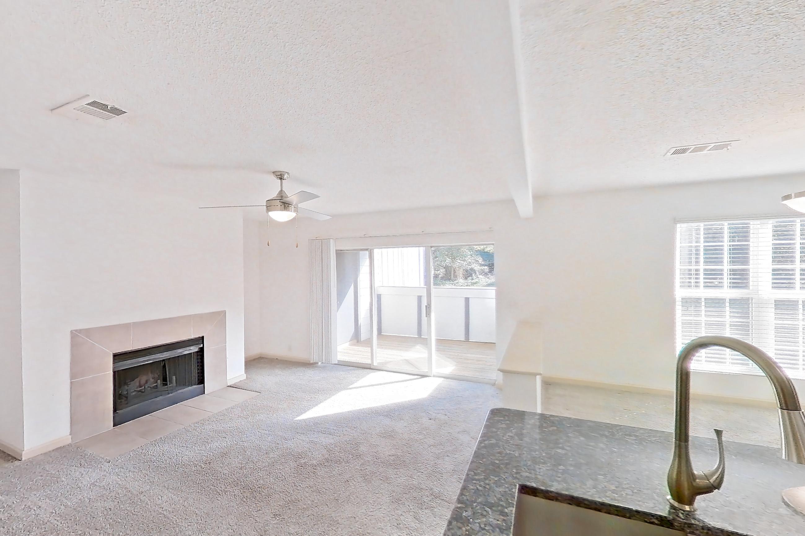 Kitchen with dark stone countertops, dishwasher, electric range, light carpet, light countertops, light wood-finish flooring, oven/range, refrigerator, and stainless steel appliances, Apartment 8 at Cortland Cotswold