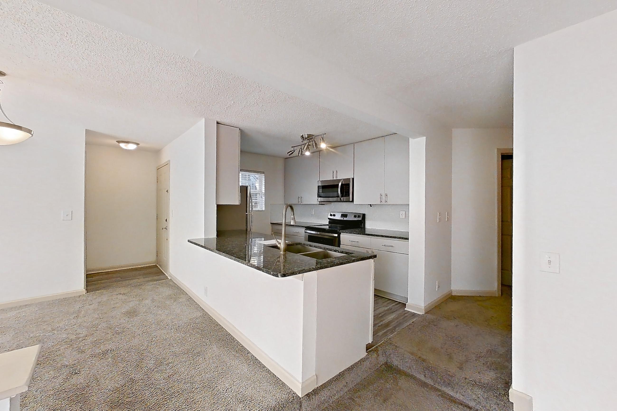 Living space with dark stone countertops, electric range, fireplace, light carpet, microwave, oven/range, stainless steel appliances, and tile fireplace, Apartment 8 at Cortland Cotswold