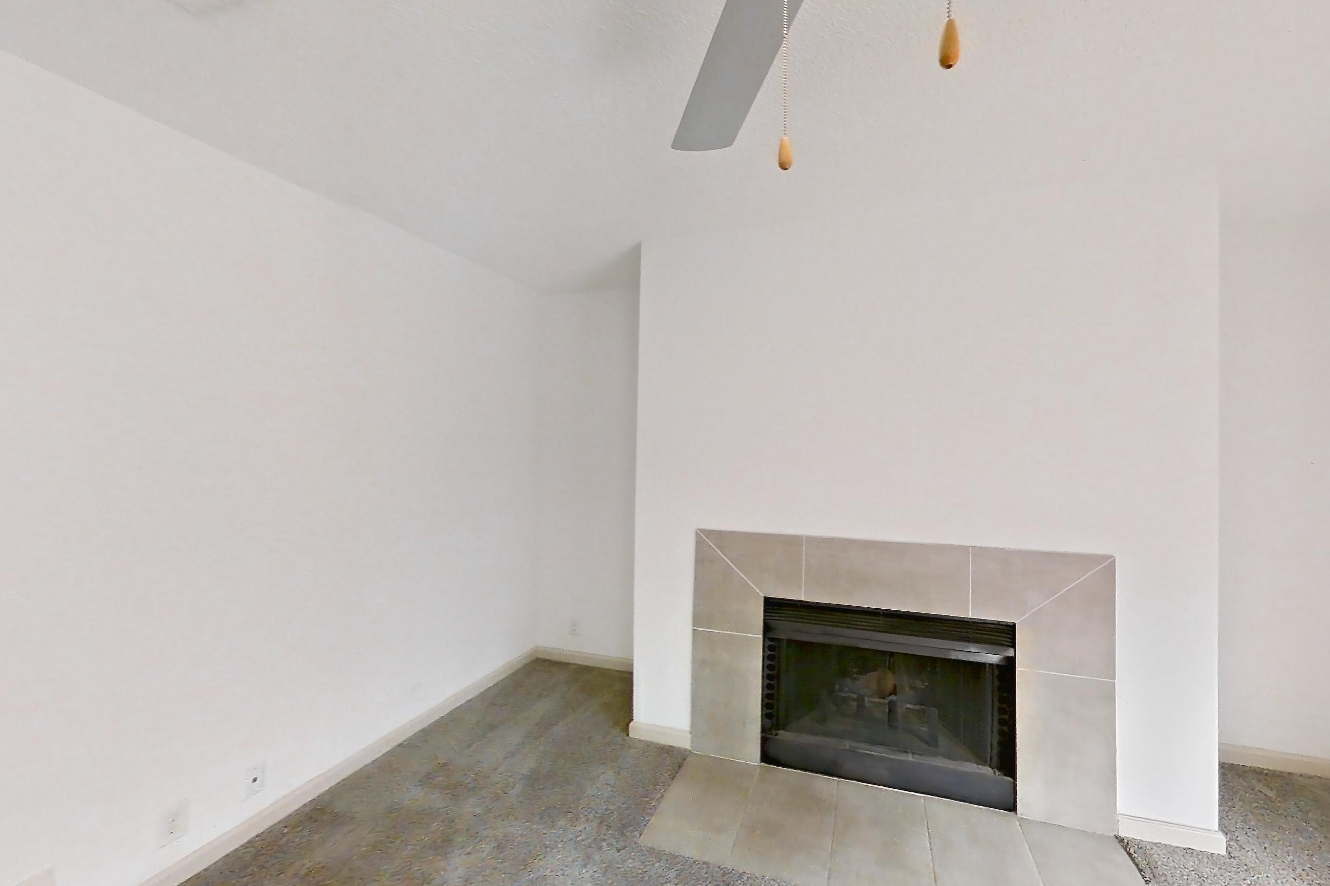 Living space with dark stone countertops, electric range, fireplace, light carpet, microwave, oven/range, stainless steel appliances, and tile fireplace, Apartment 8 at Cortland Cotswold