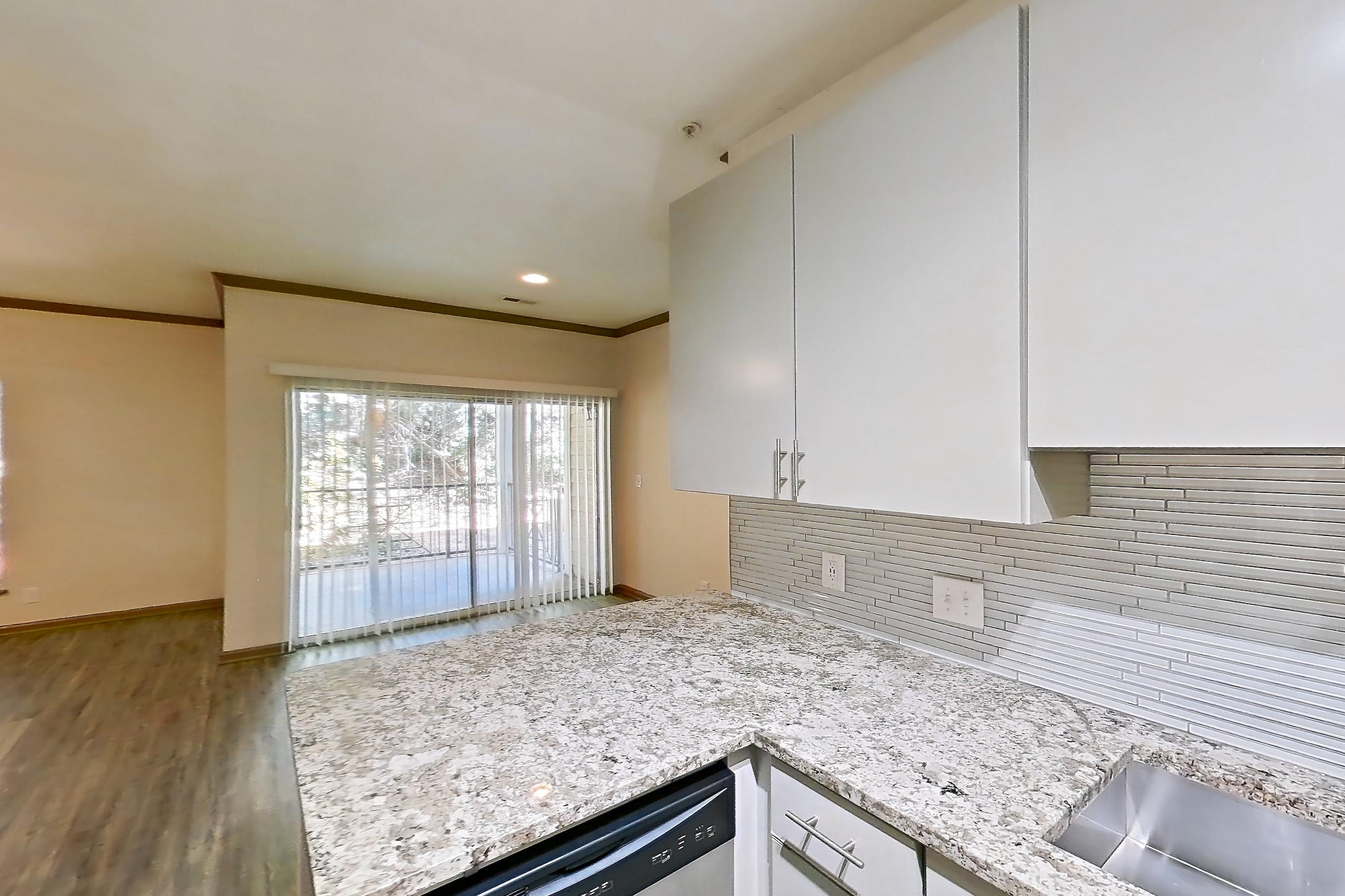 Kitchen with dishwasher, electric range, light countertops, light stone countertops, light wood-finish flooring, microwave, oven/range, refrigerator, and stainless steel appliances, Apartment 0823 at Cortland Seventy Seven