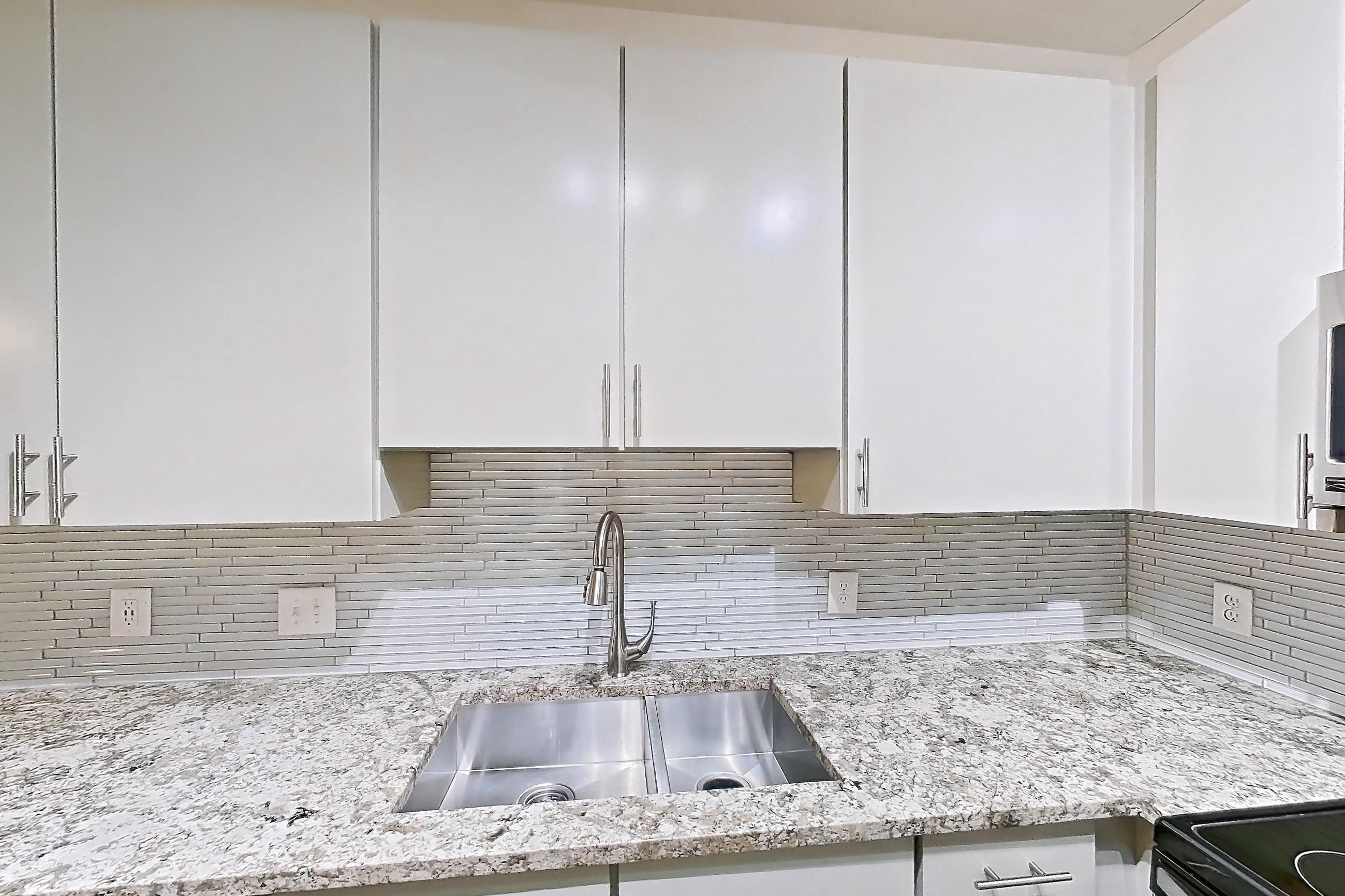 Kitchen with dishwasher, electric range, light countertops, light stone countertops, light wood-finish flooring, microwave, oven/range, refrigerator, and stainless steel appliances, Apartment 0823 at Cortland Seventy Seven