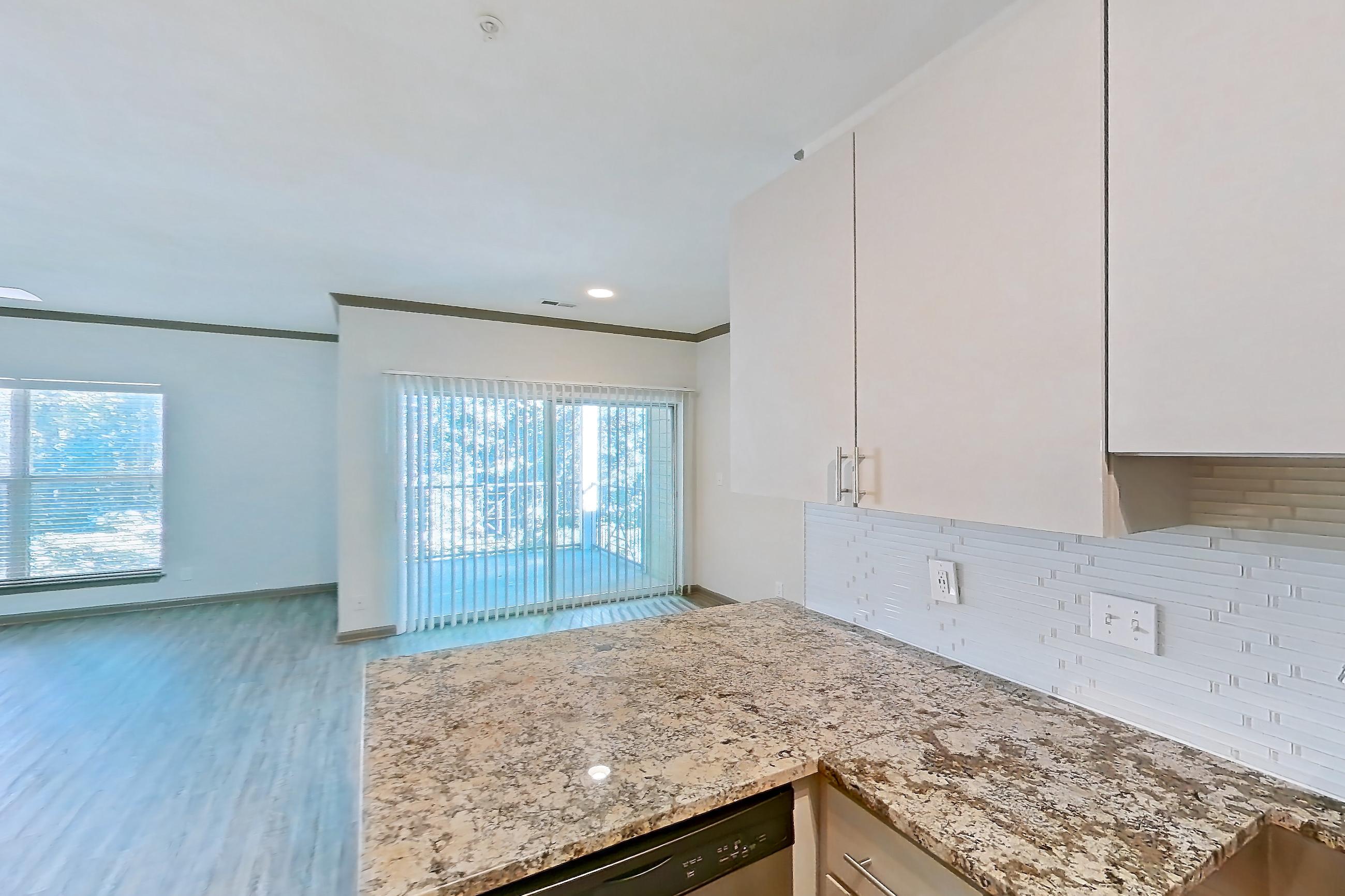 Kitchen with black appliances, dishwasher, electric range, light countertops, light stone countertops, light wood-finish flooring, microwave, oven/range, refrigerator, and stainless steel appliances, Apartment 0833 at Cortland Seventy Seven