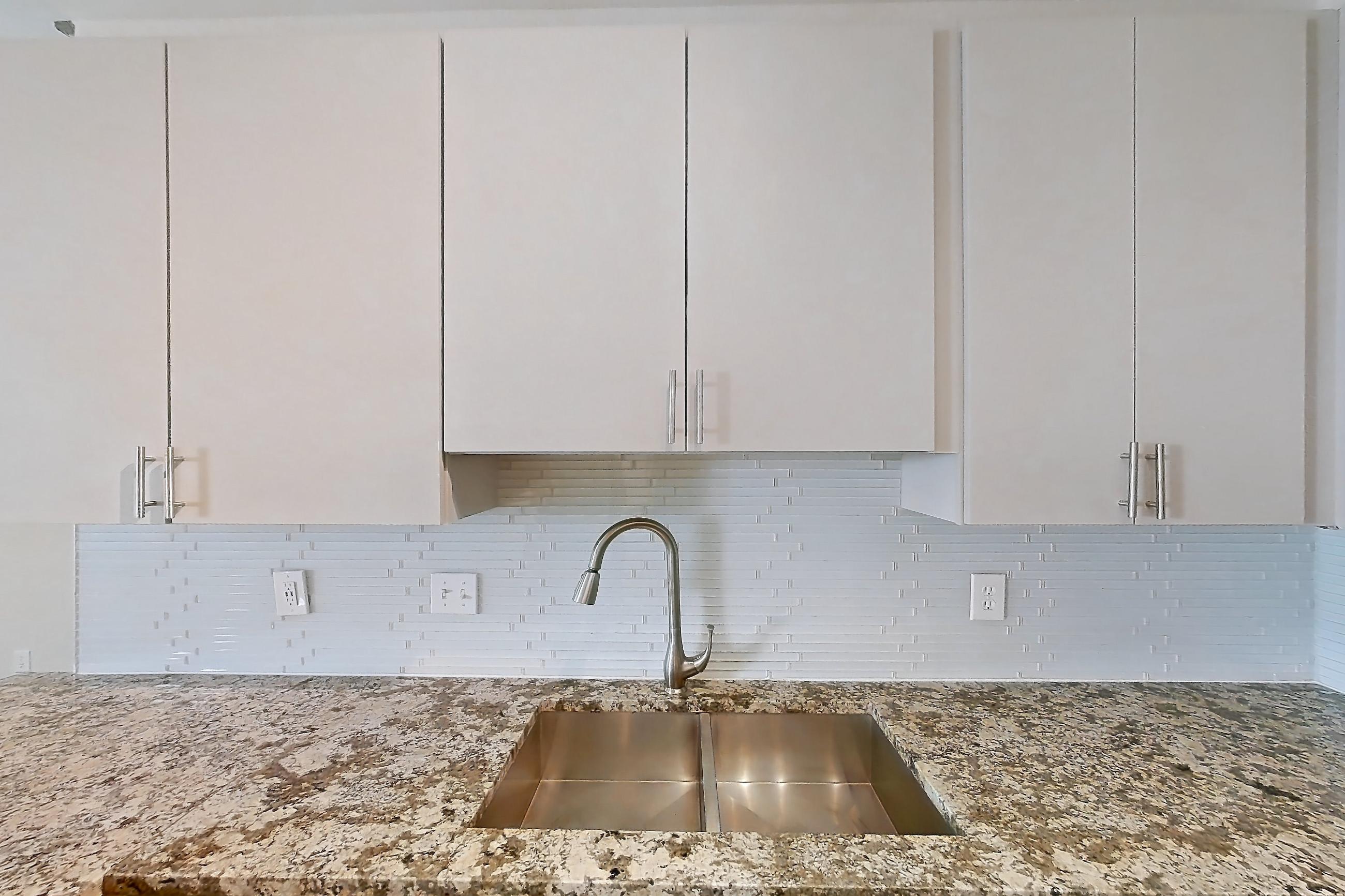 Kitchen with black appliances, dishwasher, electric range, light countertops, light stone countertops, light wood-finish flooring, microwave, oven/range, refrigerator, and stainless steel appliances, Apartment 0833 at Cortland Seventy Seven