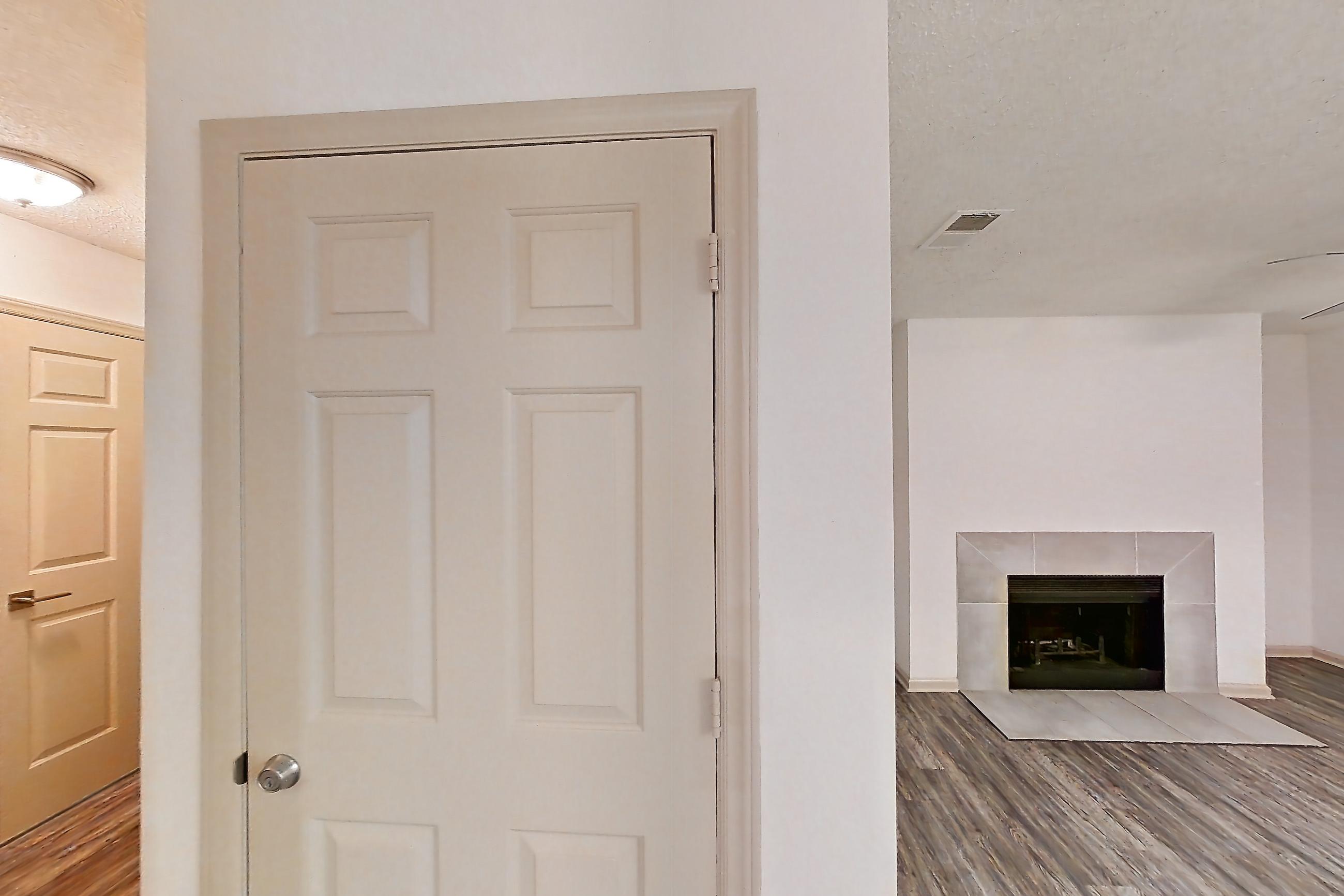 Kitchen with black appliances, dark stone countertops, dark wood-finish flooring, dishwasher, electric range, fireplace, light countertops, light wood-finish flooring, microwave, oven/range, refrigerator, and stainless steel appliances, Apartment 4 at Cortland Cotswold