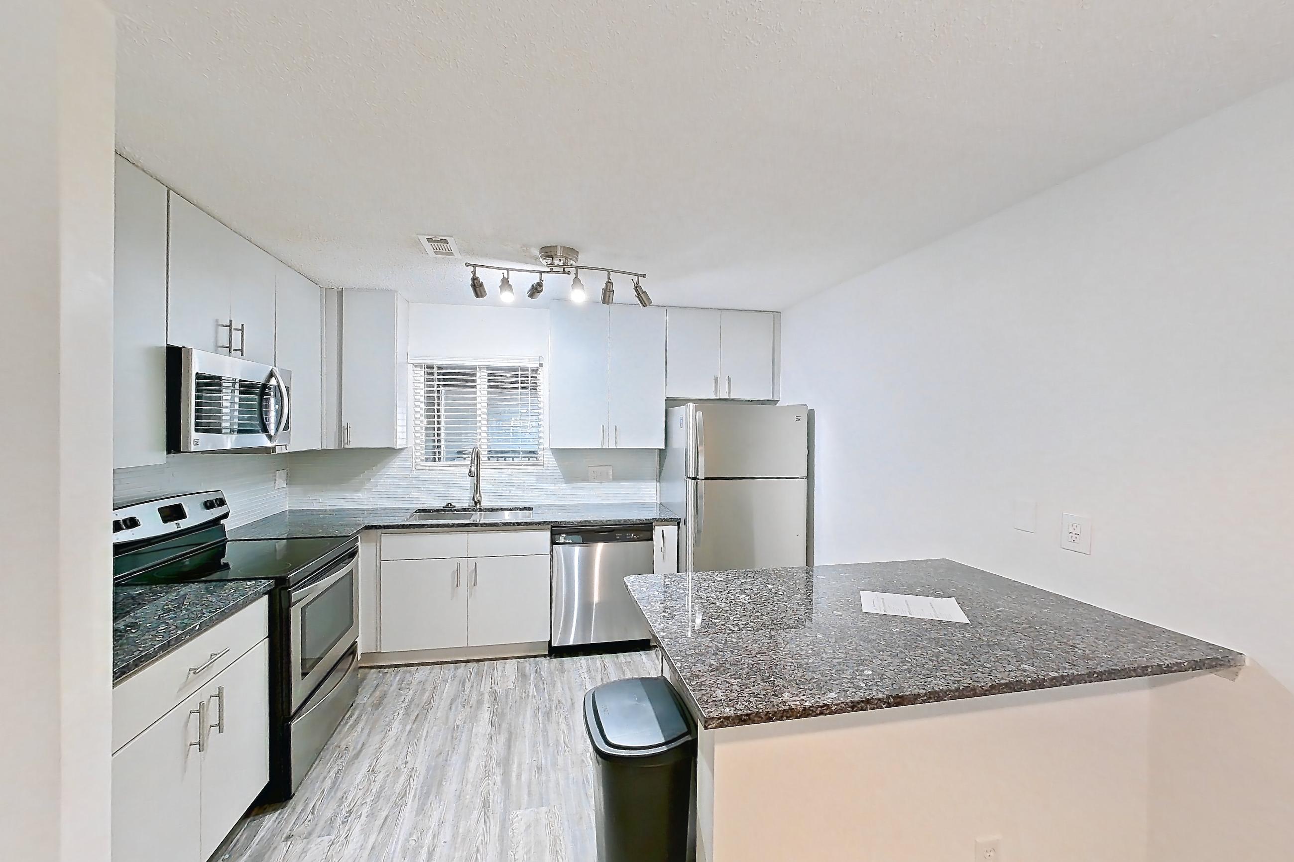 Dining room with dark stone countertops, dishwasher, electric range, fireplace, light carpet, light countertops, oven/range, refrigerator, stainless steel appliances, and tile fireplace, Apartment 9 at Cortland Cotswold