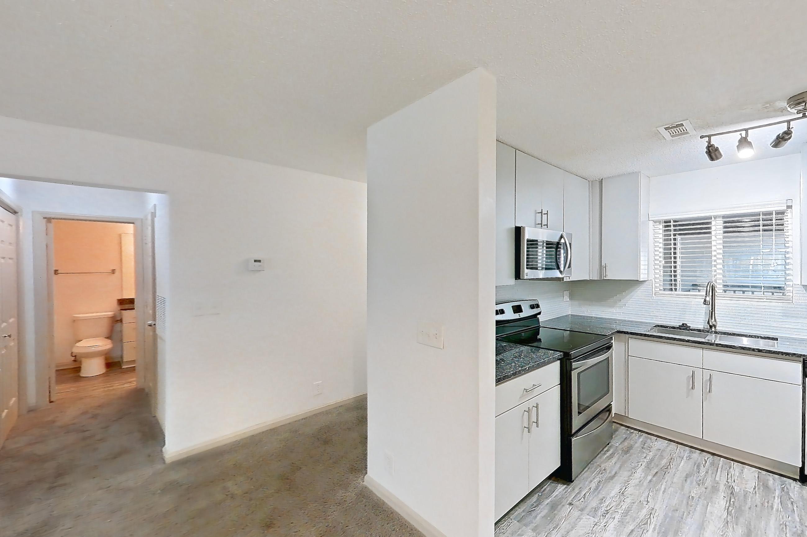 Dining room with dark stone countertops, dishwasher, electric range, fireplace, light carpet, light countertops, oven/range, refrigerator, stainless steel appliances, and tile fireplace, Apartment 9 at Cortland Cotswold