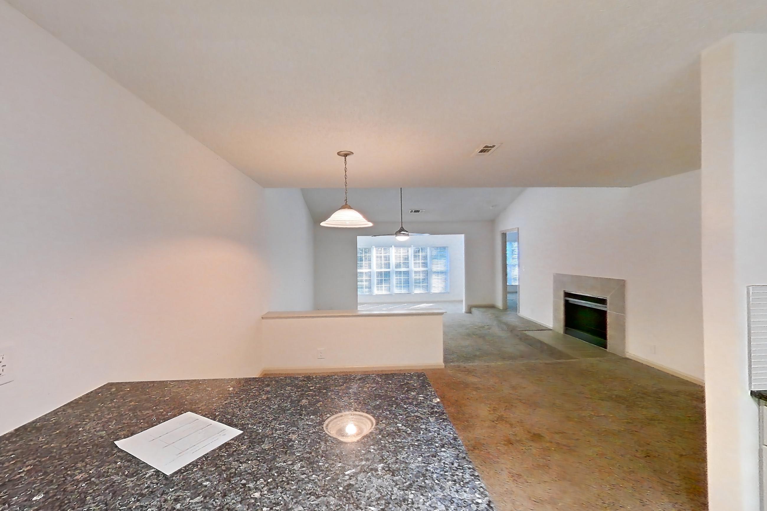 Kitchen with dark stone countertops, dishwasher, electric range, fireplace, light carpet, light countertops, light wood-finish flooring, oven/range, refrigerator, stainless steel appliances, and tile fireplace, Apartment 9 at Cortland Cotswold
