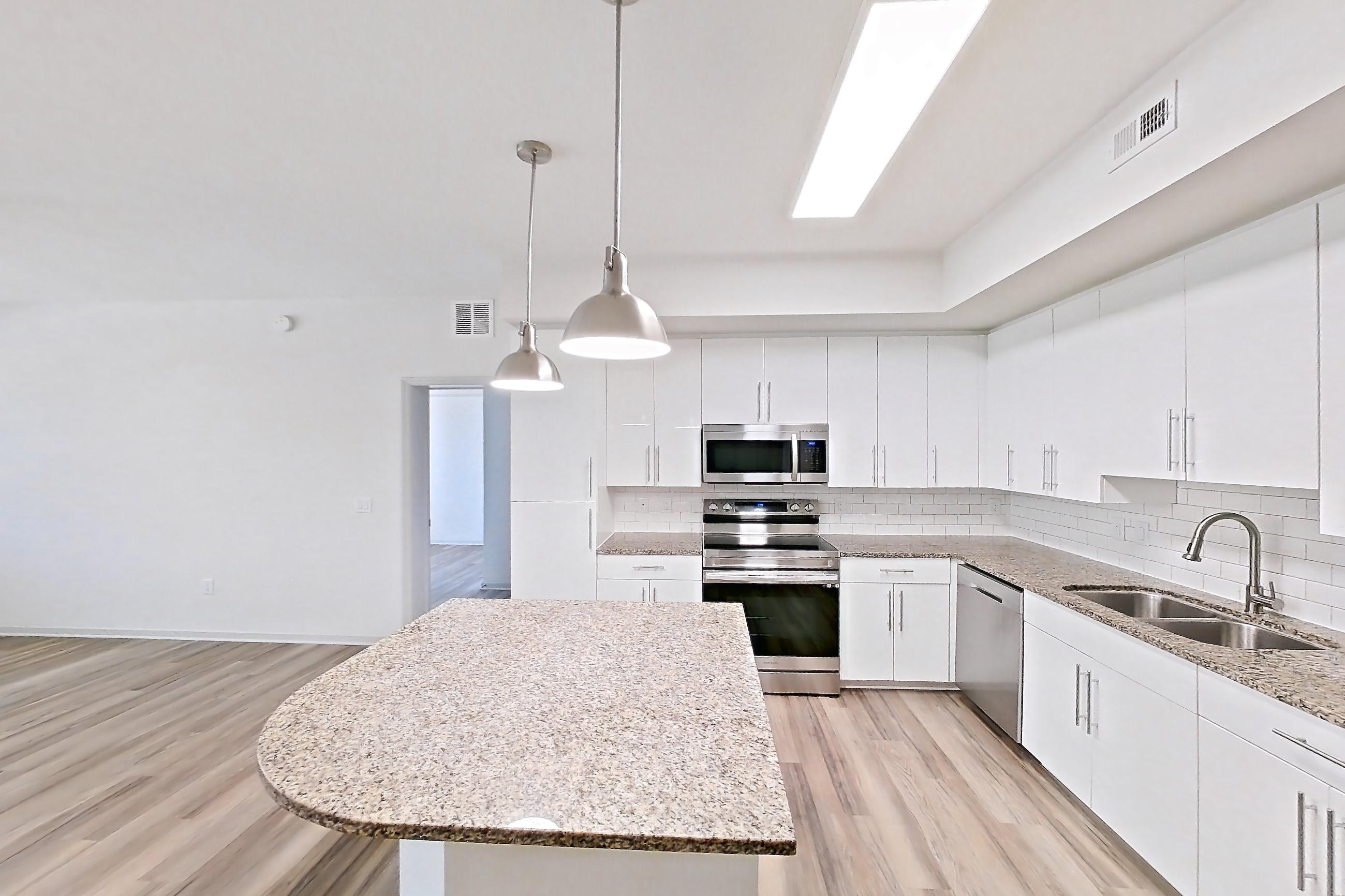 Kitchen entryway with dishwasher, electric range, light stone countertops, light wood-finish flooring, oven/range, refrigerator, and stainless steel appliances, Apartment 5-304 at Cortland West Palm