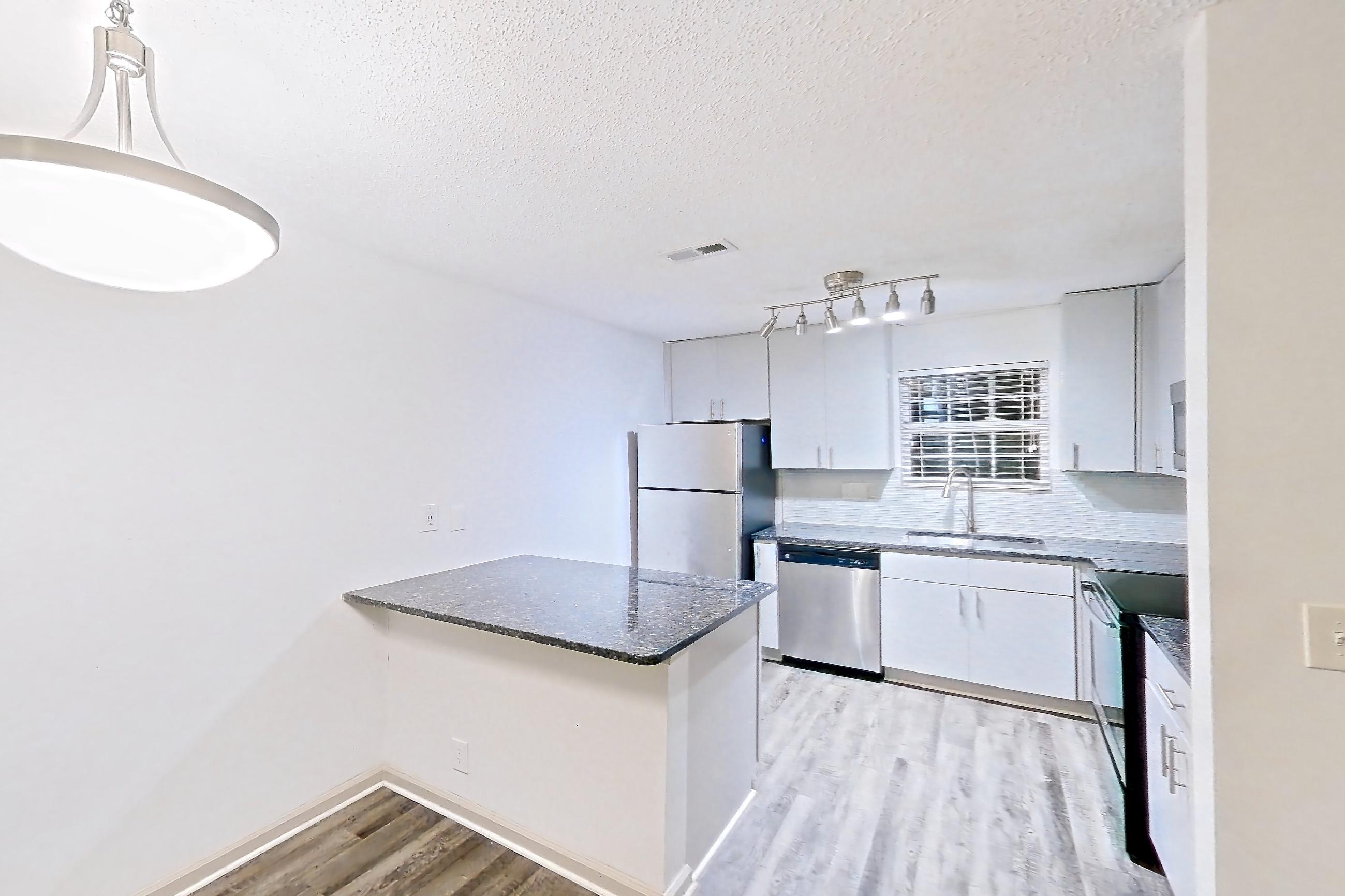 Dining room with dark stone countertops, dark wood-finish flooring, dishwasher, electric range, fireplace, light wood-finish flooring, refrigerator, stainless steel appliances, and tile fireplace, Apartment 2 at Cortland Cotswold
