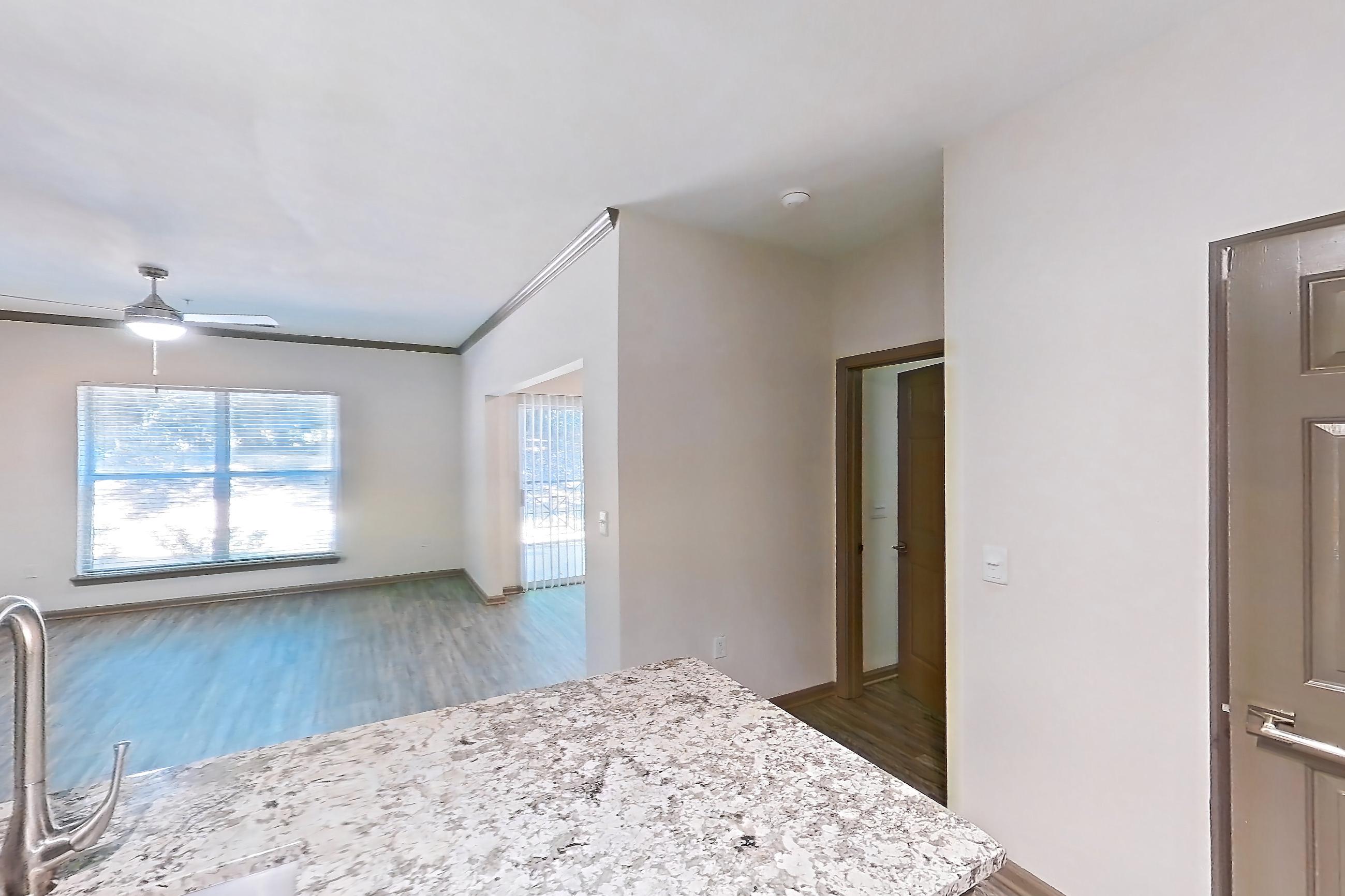 Kitchen with dishwasher, electric range, kitchen island, light countertops, light stone countertops, light wood-finish flooring, microwave, oven/range, refrigerator, and stainless steel appliances, Apartment 1317 at Cortland Seventy Seven