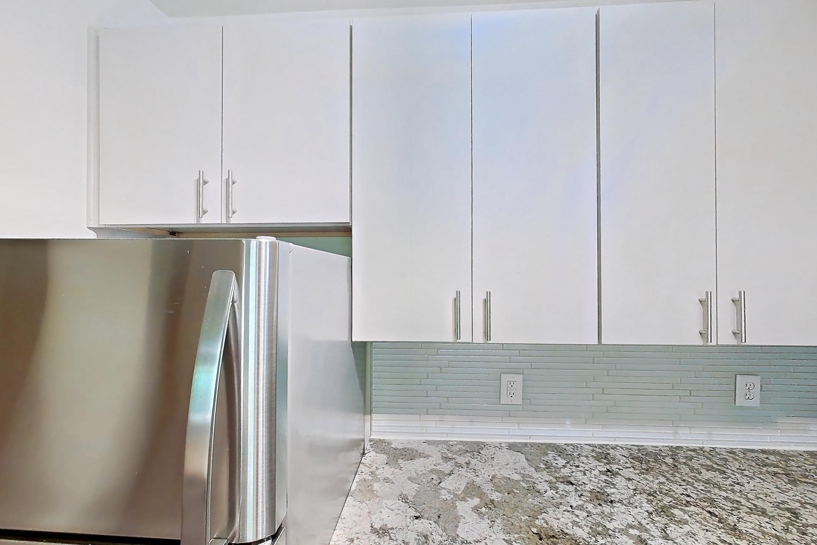 Kitchen with dishwasher, electric range, light countertops, light stone countertops, light wood-finish flooring, microwave, oven/range, and stainless steel appliances, Apartment 1337 at Cortland Seventy Seven