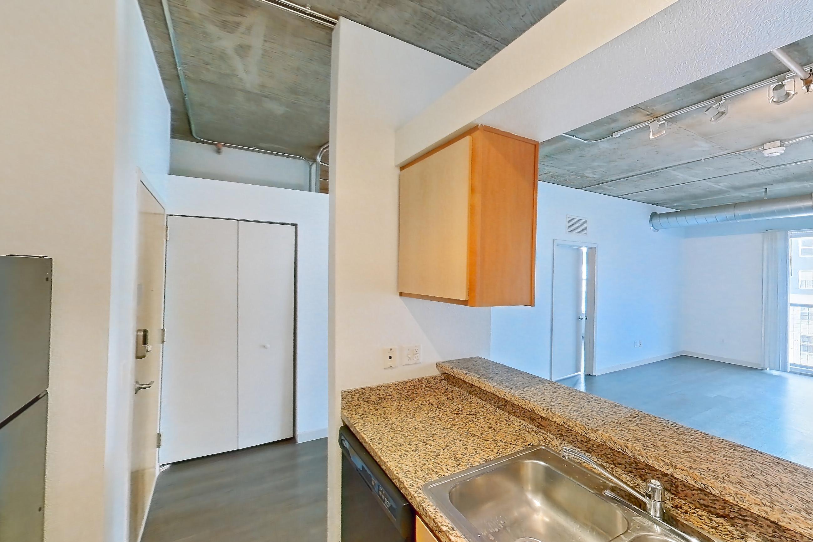 Kitchen with black appliances, dark stone countertops, dark wood-finish flooring, dishwasher, electric range, light stone countertops, light wood-finish flooring, microwave, oven/range, and refrigerator, Apartment 1439 at Cortland on Blake