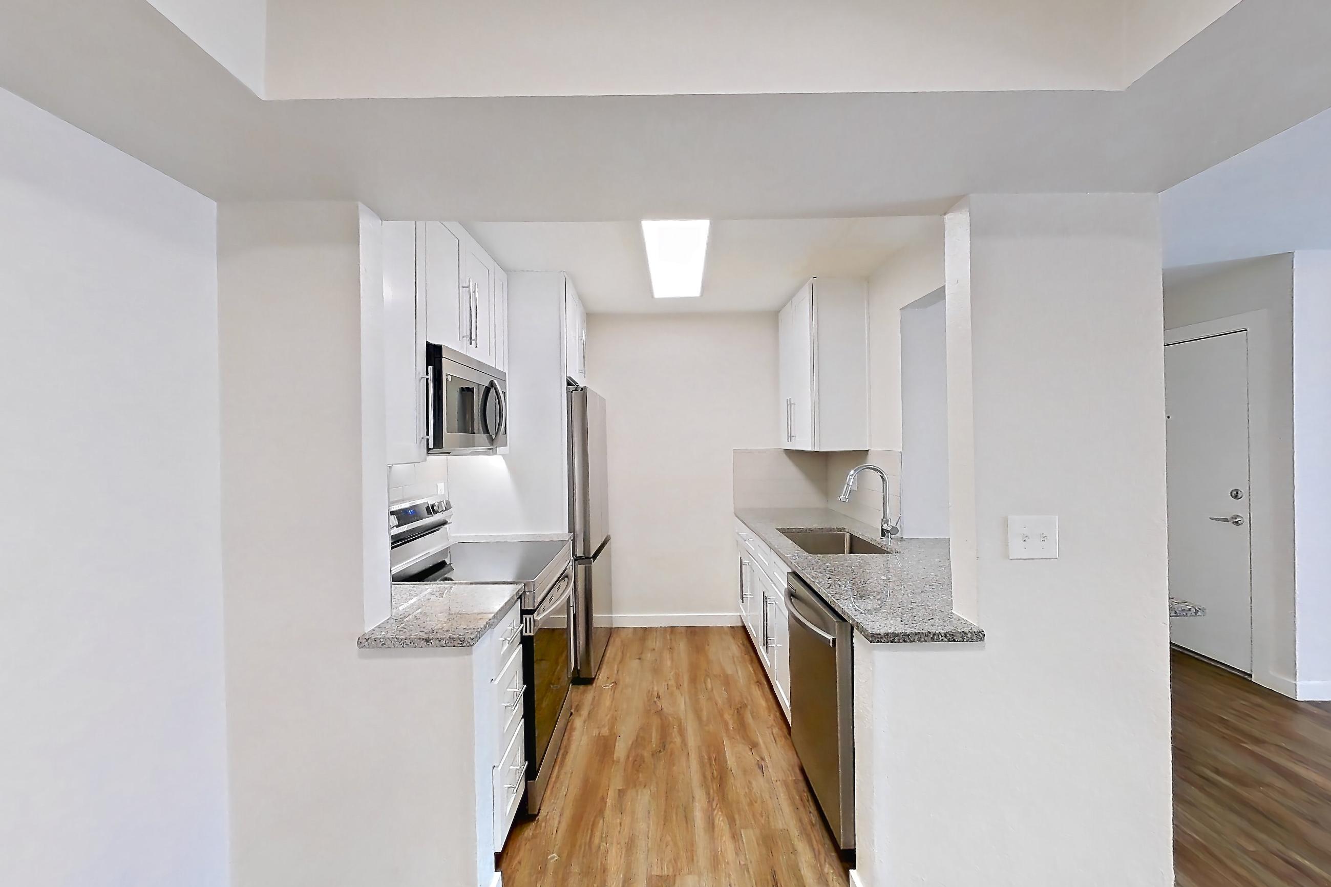 Dining room with dark wood-finish flooring, dishwasher, electric range, light countertops, light stone countertops, light wood-finish flooring, microwave, oven/range, refrigerator, and stainless steel appliances, Apartment 226 at Cortland Sun River