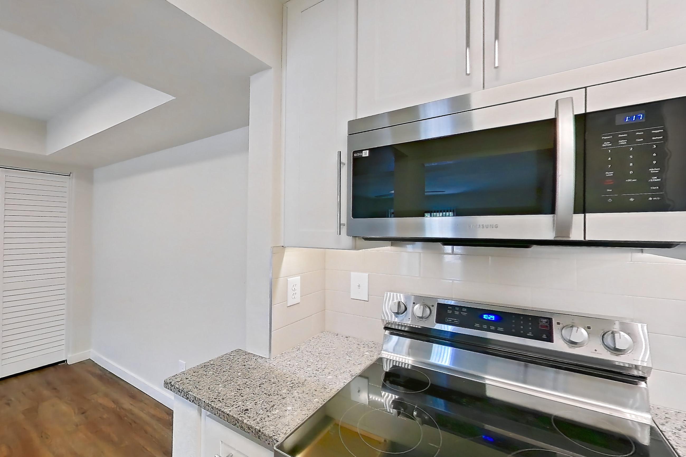 Kitchen with dishwasher, electric range, light countertops, light stone countertops, light wood-finish flooring, microwave, oven/range, refrigerator, and stainless steel appliances, Apartment 226 at Cortland Sun River
