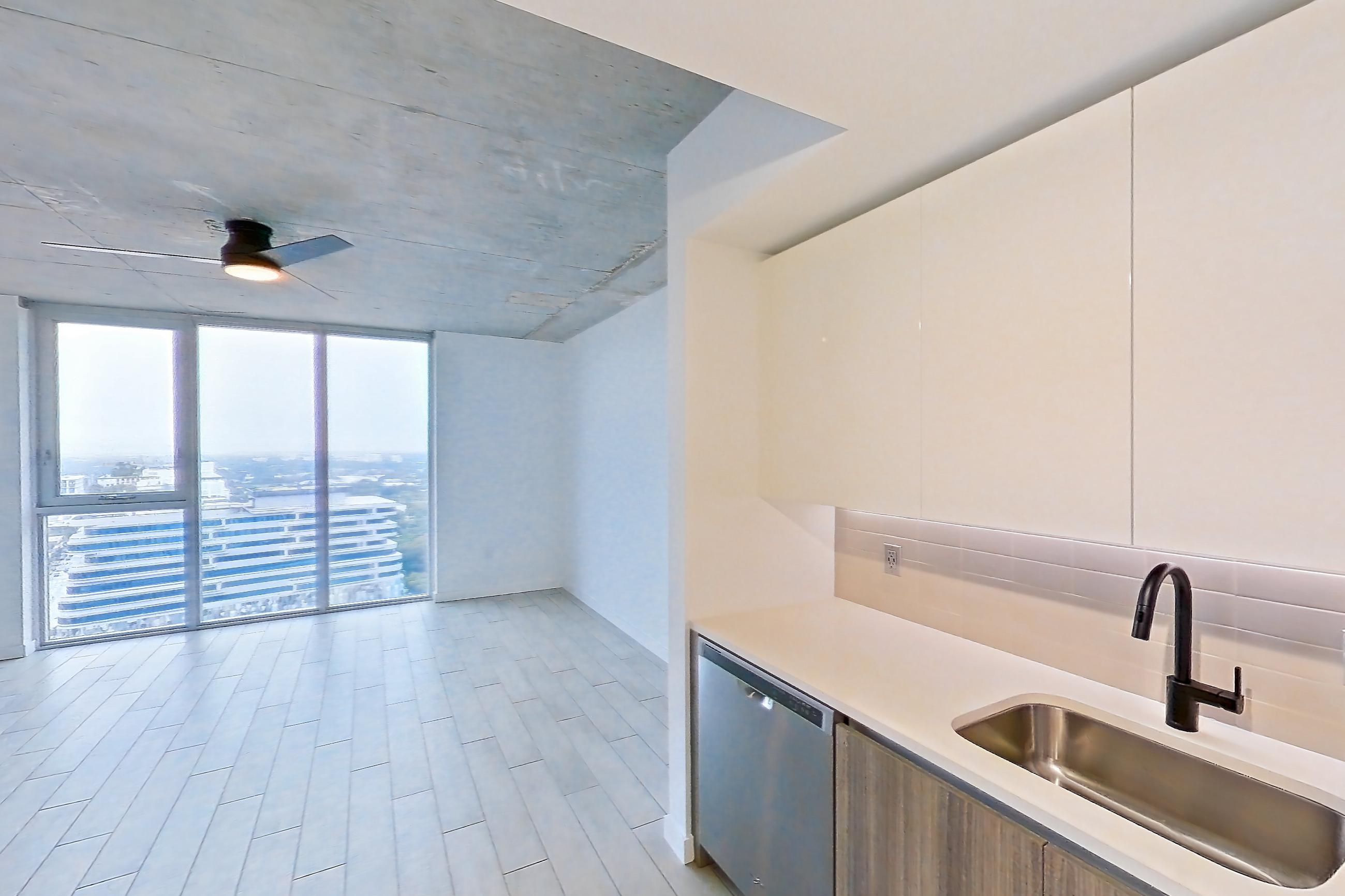 Kitchen with dishwasher, electric range, light countertops, light stone countertops, light tile flooring, light wood-finish flooring, microwave, oven/range, refrigerator, stainless steel appliances, water & ice dispenser, and wood-look tile flooring, Apartment 2518 at Cortland Midtown Miami