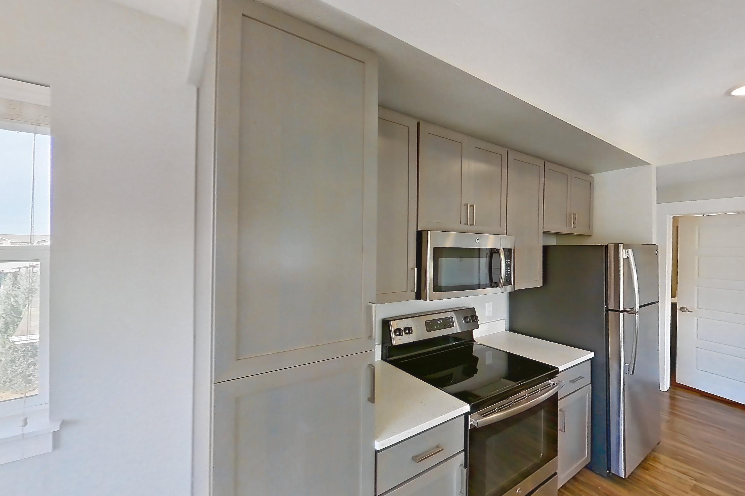 Dining room with dark wood-finish flooring, electric range, light countertops, microwave, oven/range, and stainless steel appliances, Apartment H205 at Cortland at Ten Mile