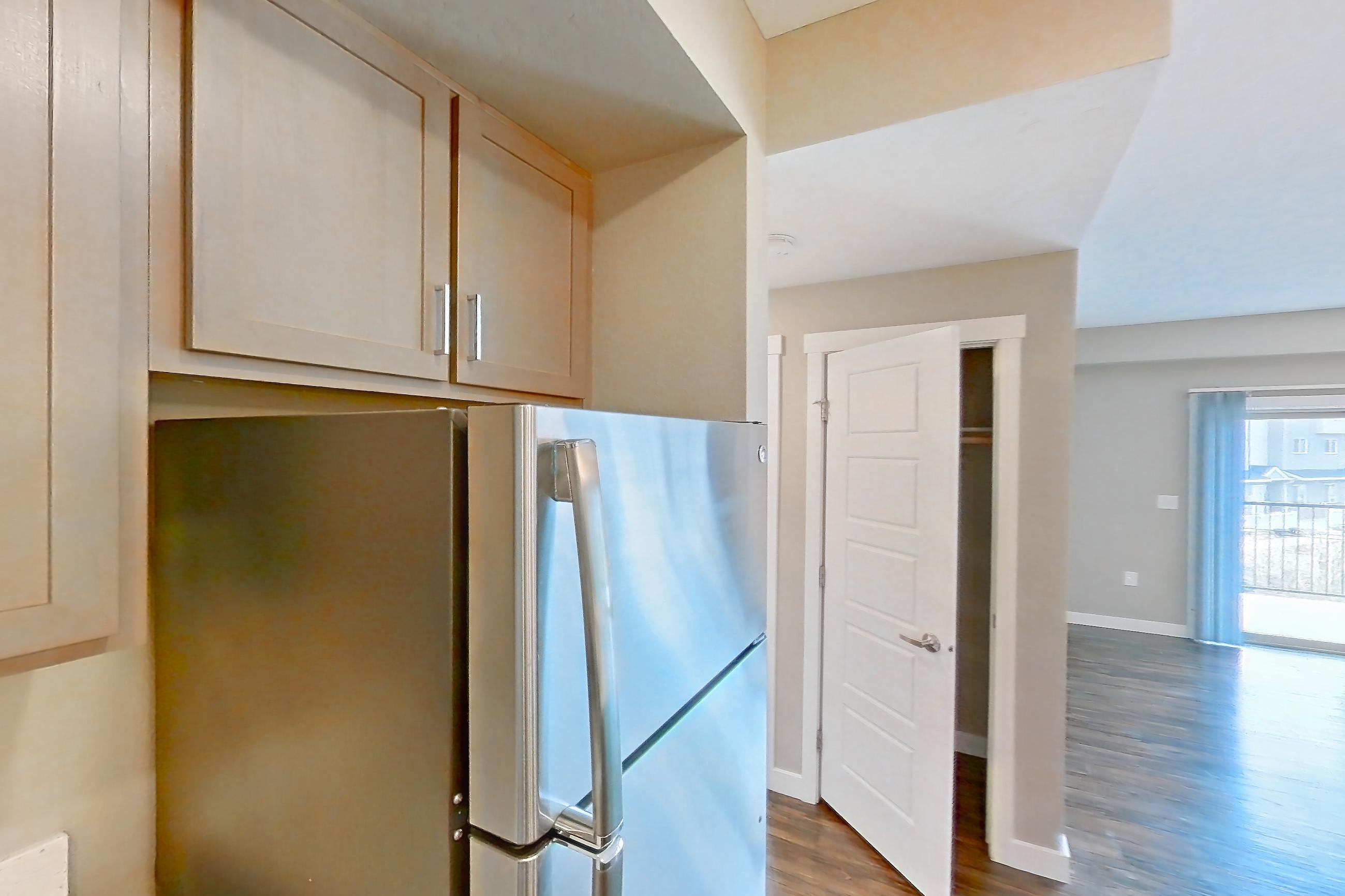 Kitchen with dark wood-finish flooring, dishwasher, electric range, light countertops, light stone countertops, microwave, oven/range, refrigerator, and stainless steel appliances, Apartment B208 at Cortland at Ten Mile