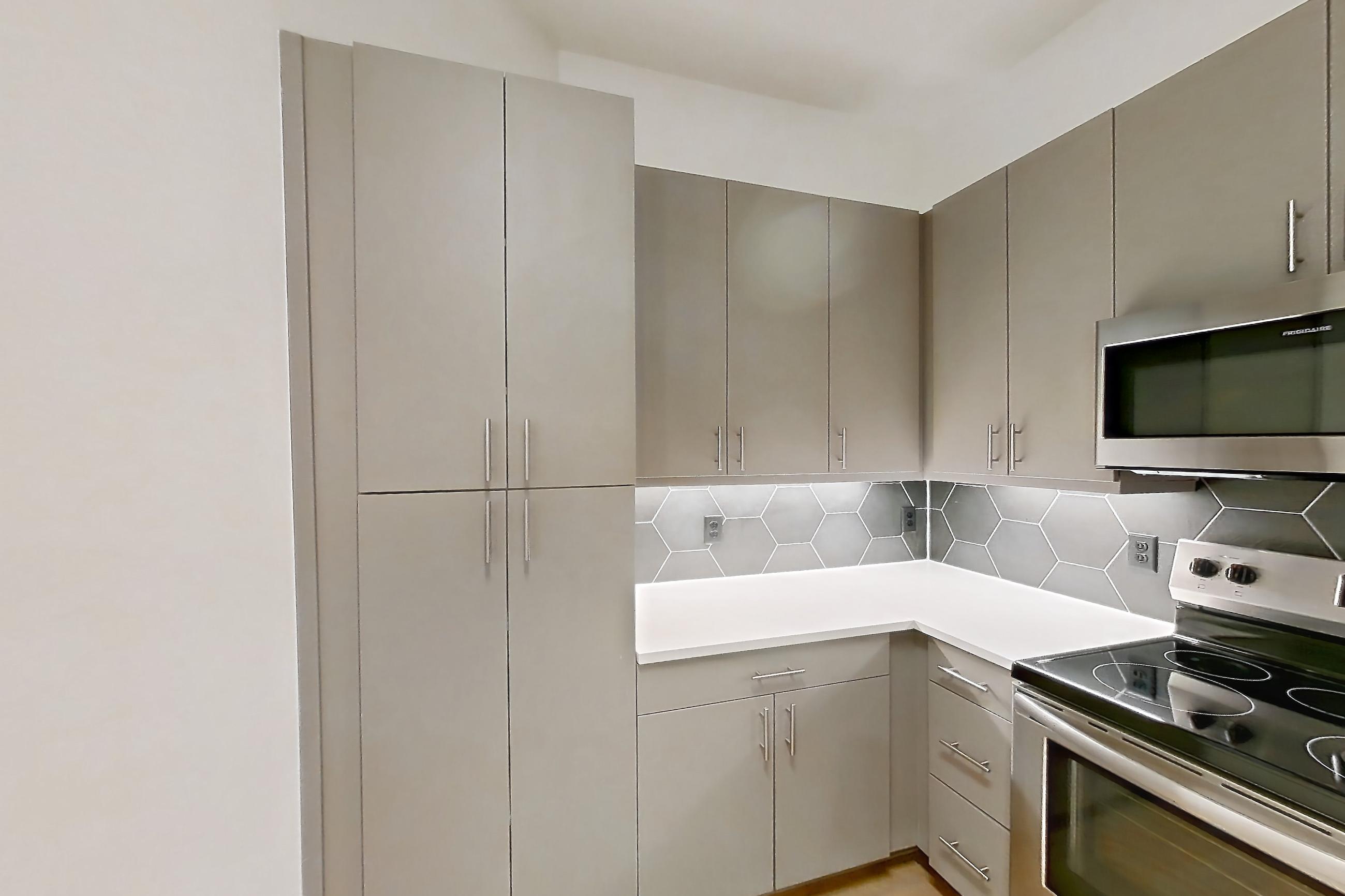 Kitchen with electric range, light countertops, light wood-finish flooring, oven/range, refrigerator, and stainless steel appliances, Apartment 7408 at Cortland Satori